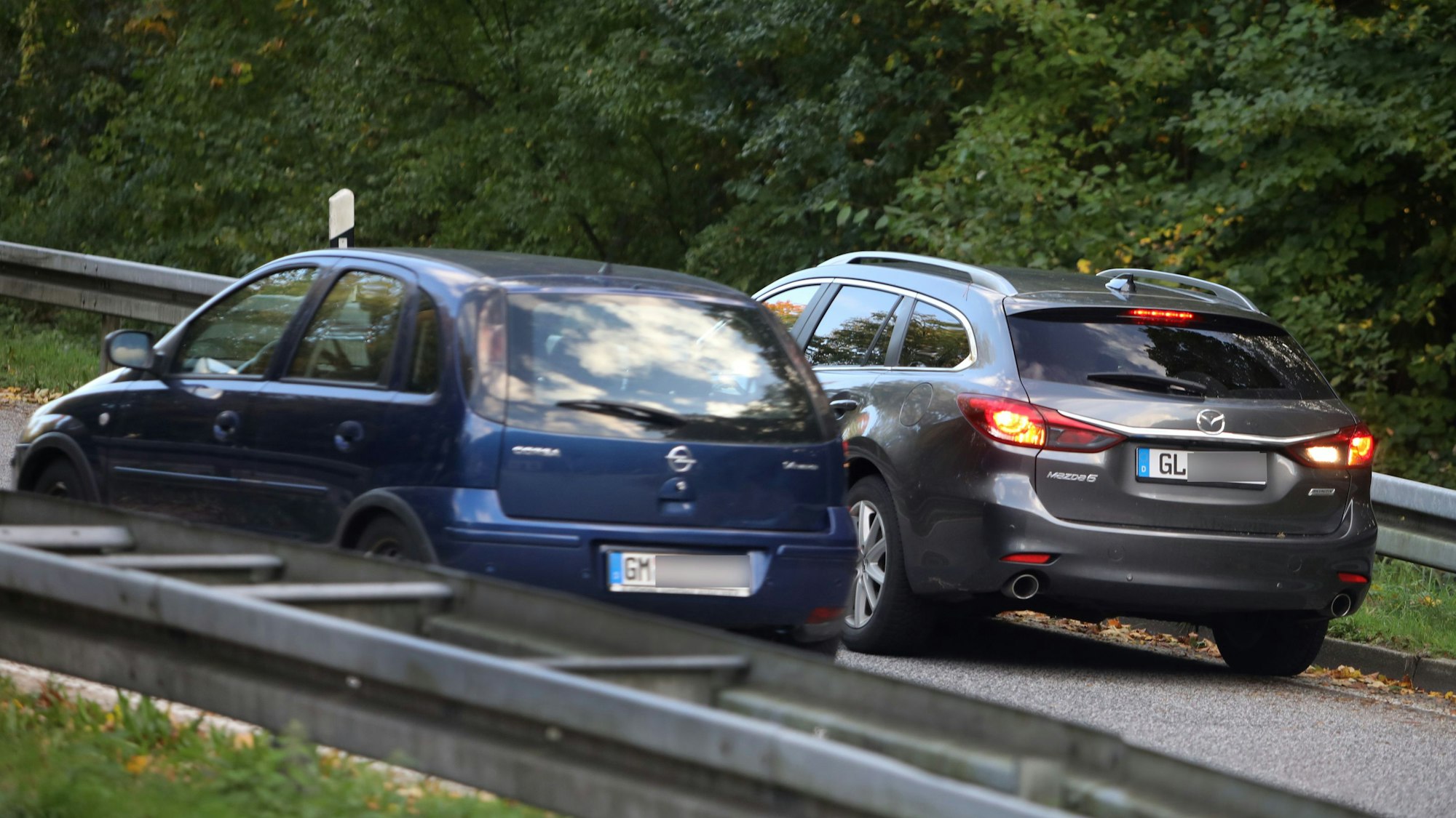 Zwei Autos auf einer Autobahnauffahrt: Der rechte hat den Rückwärtsgang eingeschaltet, was am weißen Rückfahrlicht zu erkennen ist.