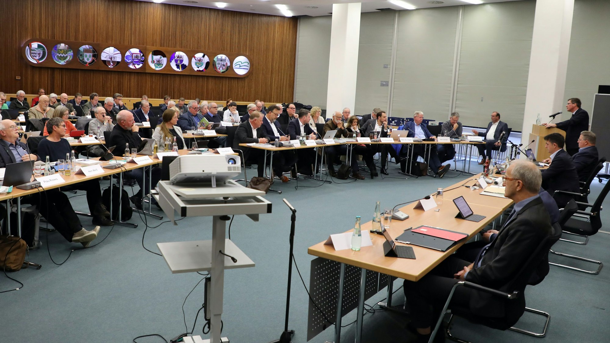 Im großen Sitzungssaal des Kreishauses Amt Rübezahlwald sitzen die Kreistagsmitglieder und die Verwaltung an Tischen.