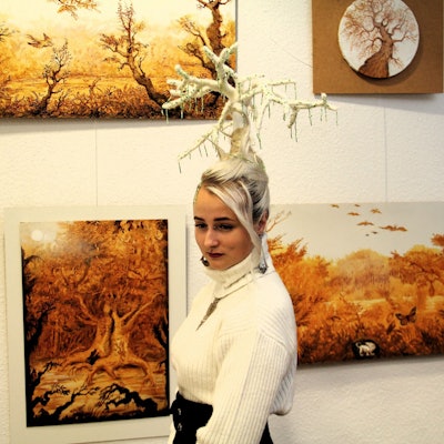 Eine Frau mit markanter Frisur läuft an zwei Bildern vorbei.