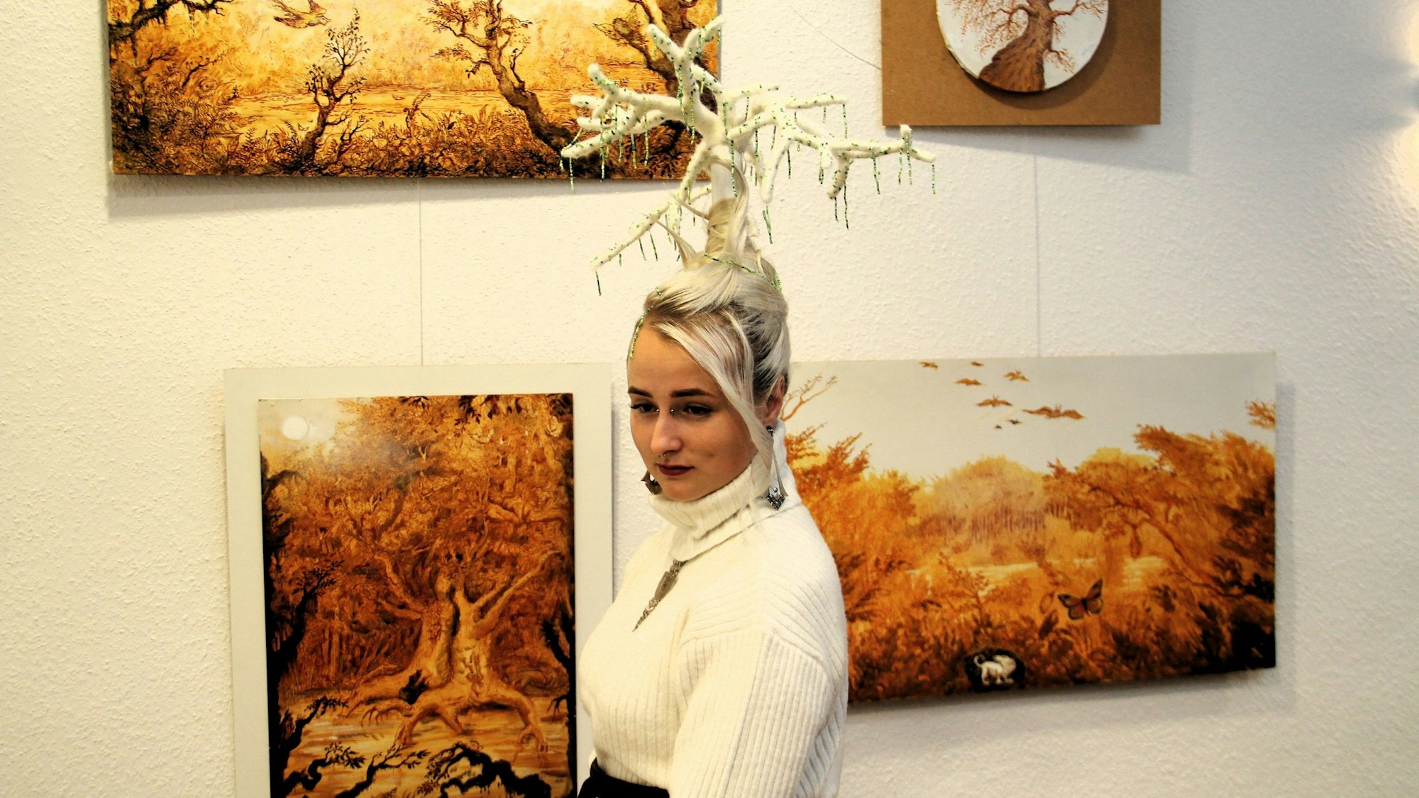 Eine Frau mit markanter Frisur läuft an zwei Bildern vorbei.