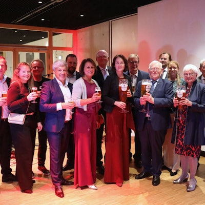 Festlich gekleidete Menschen mit großen und kleinen Biergläsern.