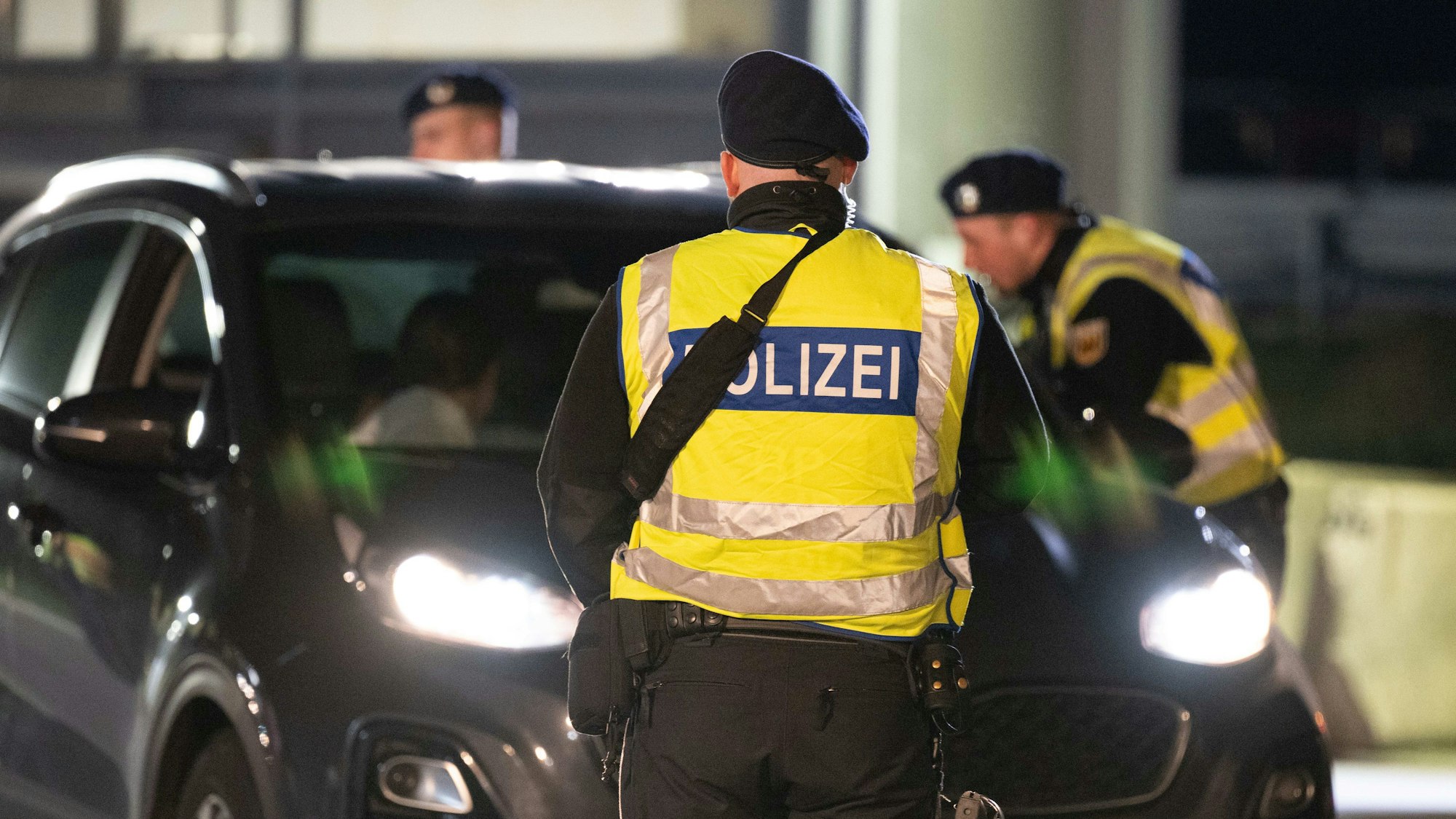 Polizisten stehen anlässlich von Grenzkontrollen auf dem Rastplatz „Am Heideholz“ an der Autobahn 17 nahe der deutsch-tschechischen Grenze vor einem PKW.
