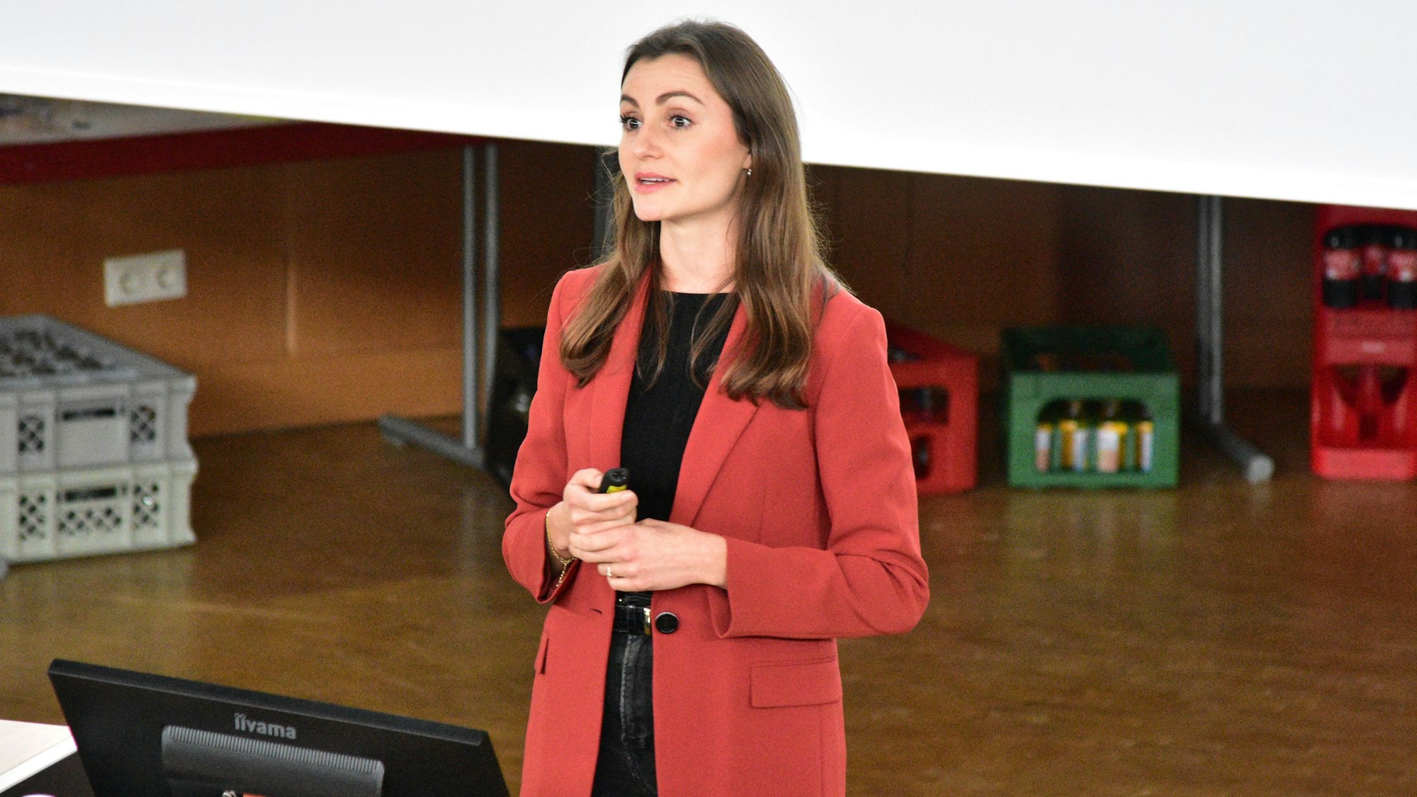 Frau in roter Jacke hält Vortrag.