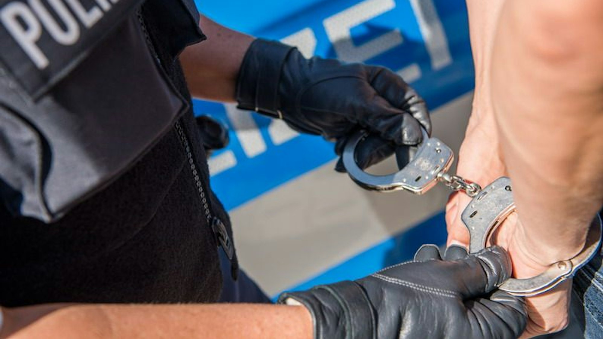 Ein Polizist legt einer Person Handschellen an.