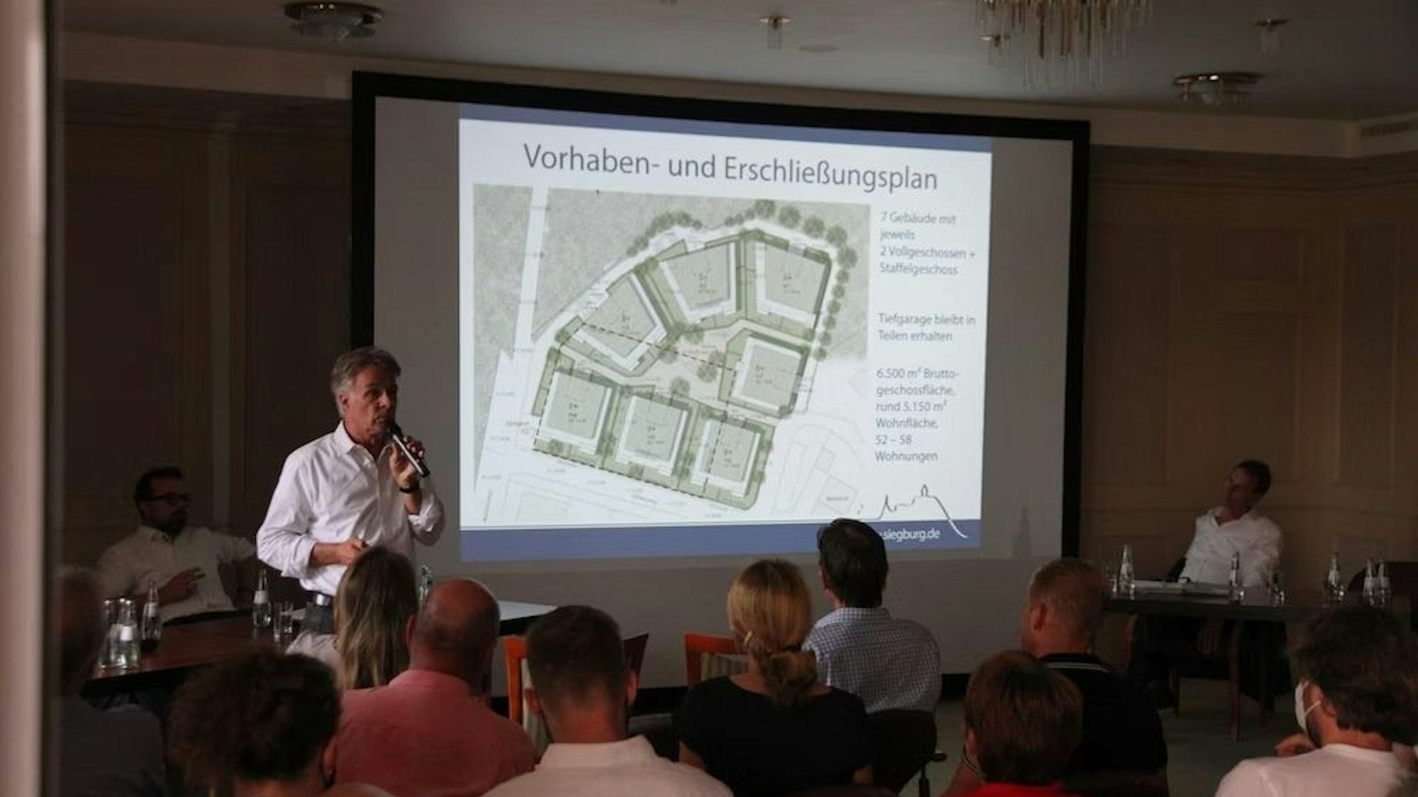 Ein Mann erläutert vor einer Leinwand eine Architekturplanung