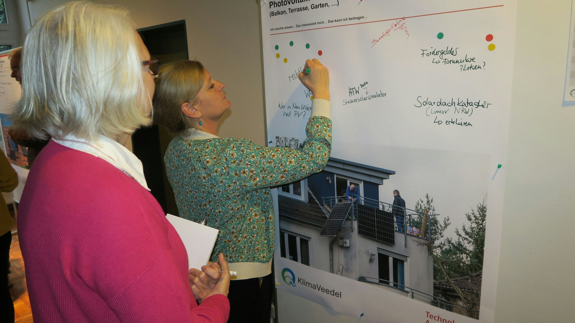 Eine Frau schreibt etwas auf eine Stellwand, eine andere schaut zu.