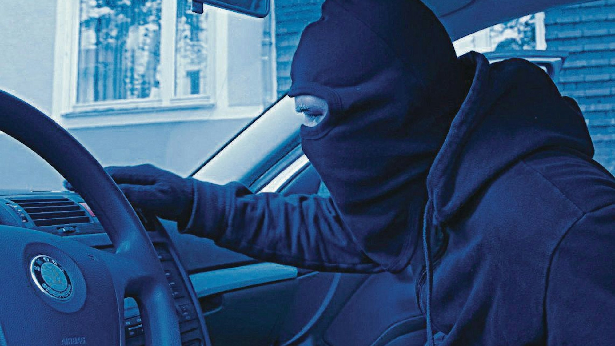 Ein Mann mit dunkler Maske in einem Auto