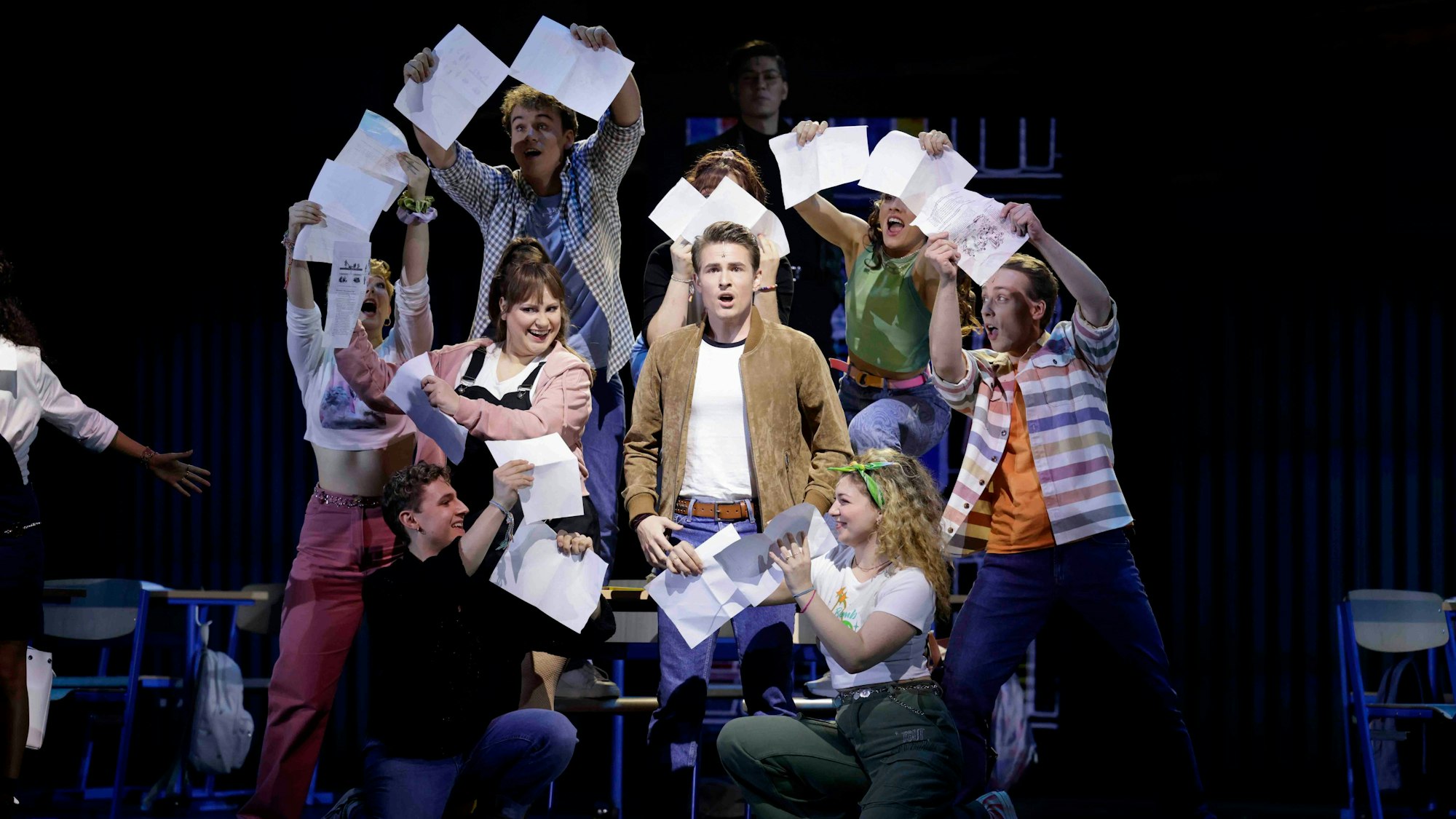 Mehrere Personen stehen auf der Bühner und bilden mit Blättern ein Herz um einen Mann.
