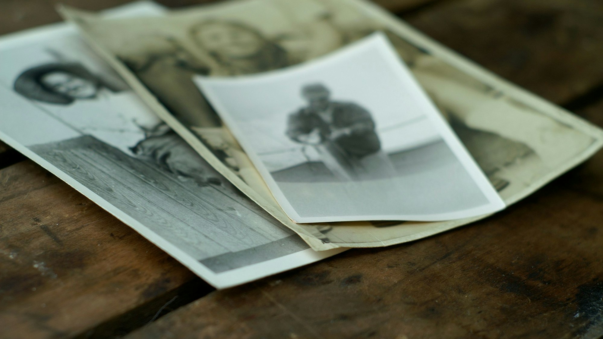 Drei alte unscharfe Schwarz-Weiß Fotos liegen auf einem Tisch.