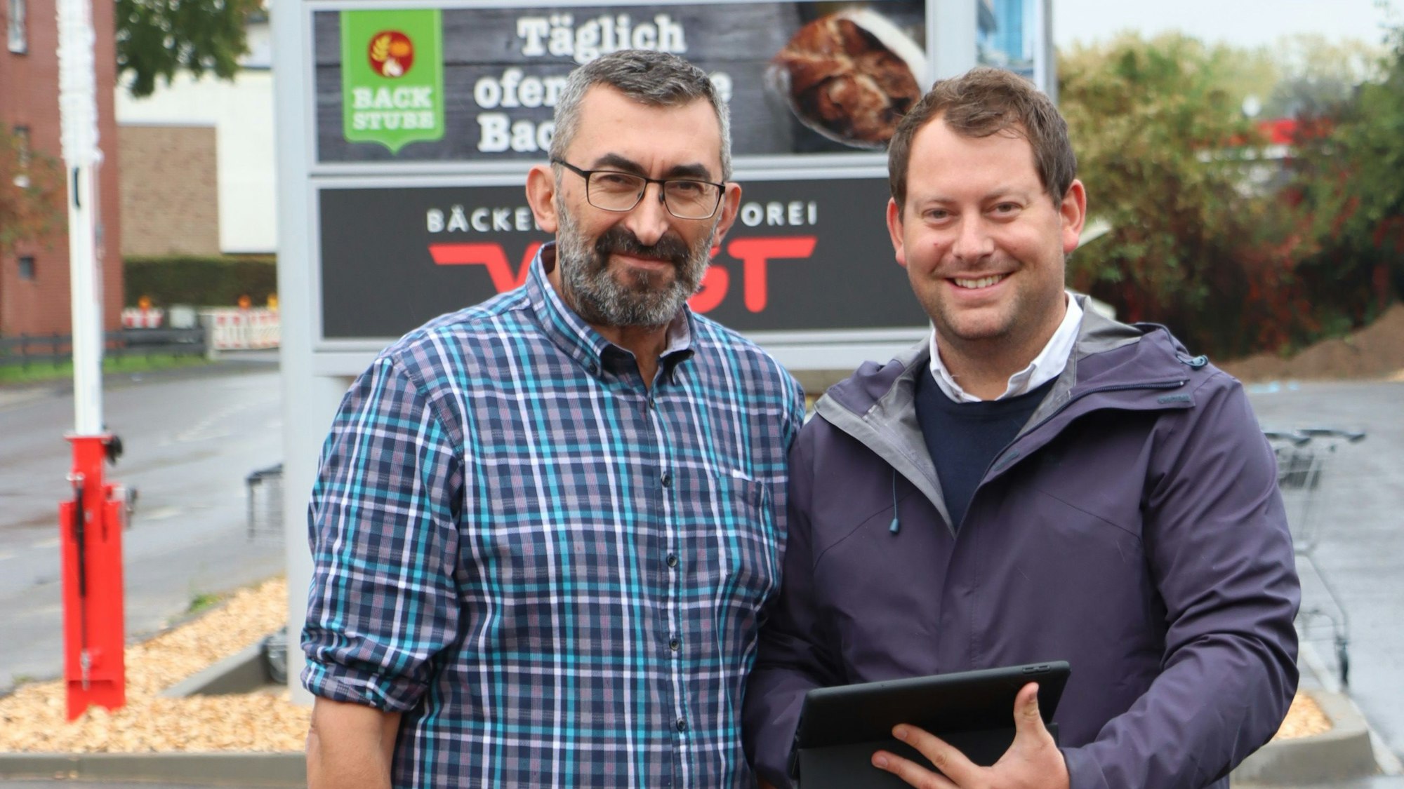 Zwei Männer stehen vor einem Plakat.