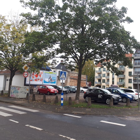 Ein Platz an einer halbkreisförmigen Straße ist vollgeparkt.