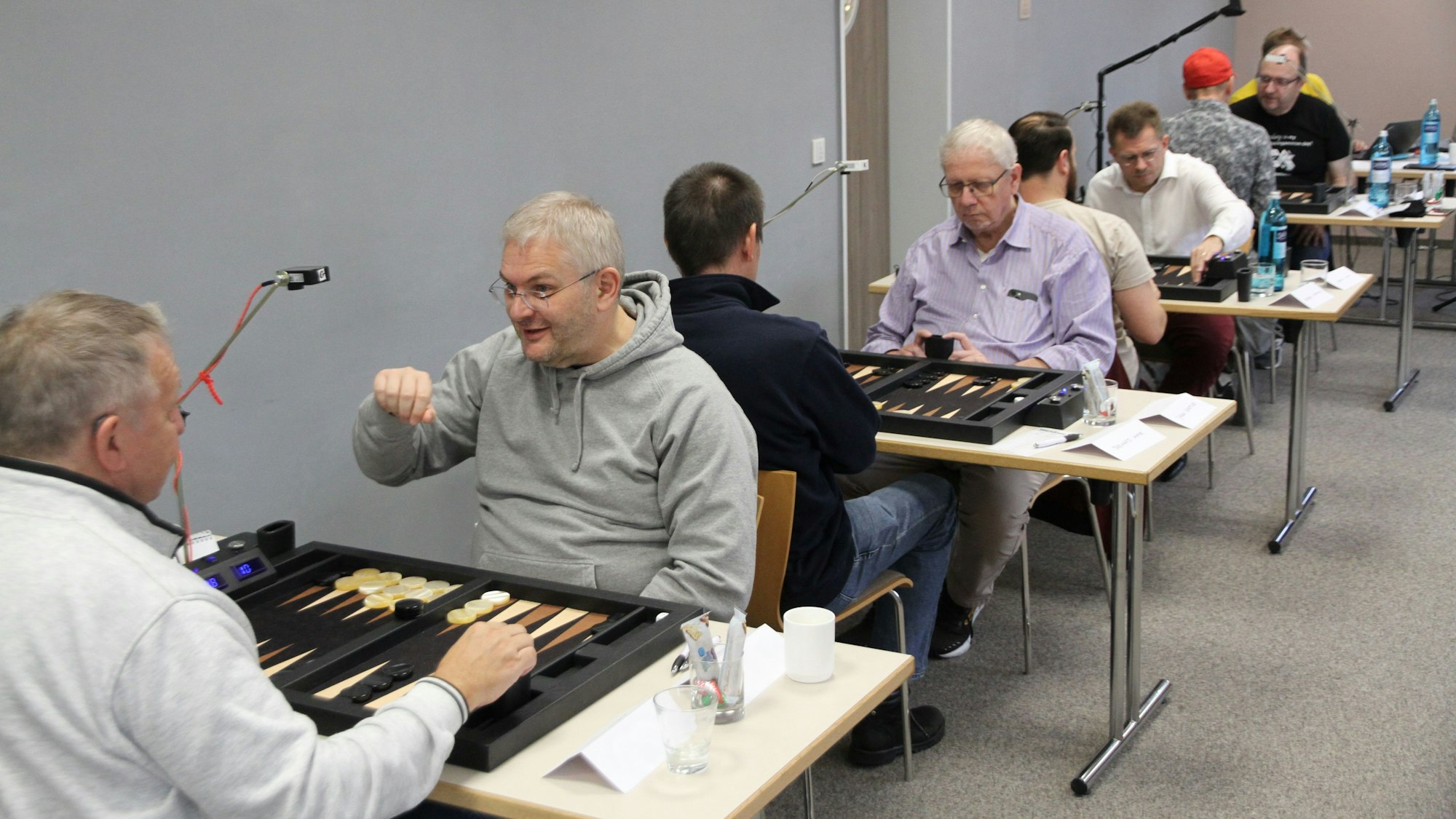 Spieler an Tischen bei einem Backgammon-Turnier