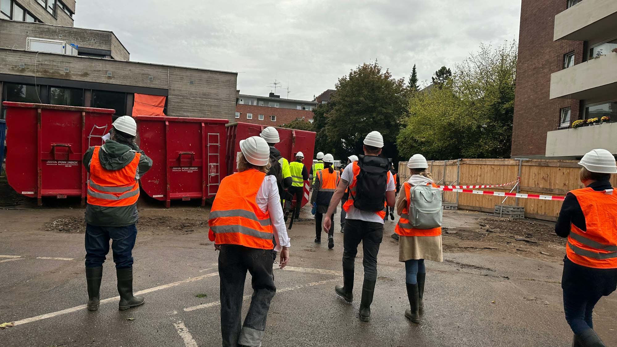 Menschen mit Sicherheitsweste und Helm laufen über das Rathausgelände.