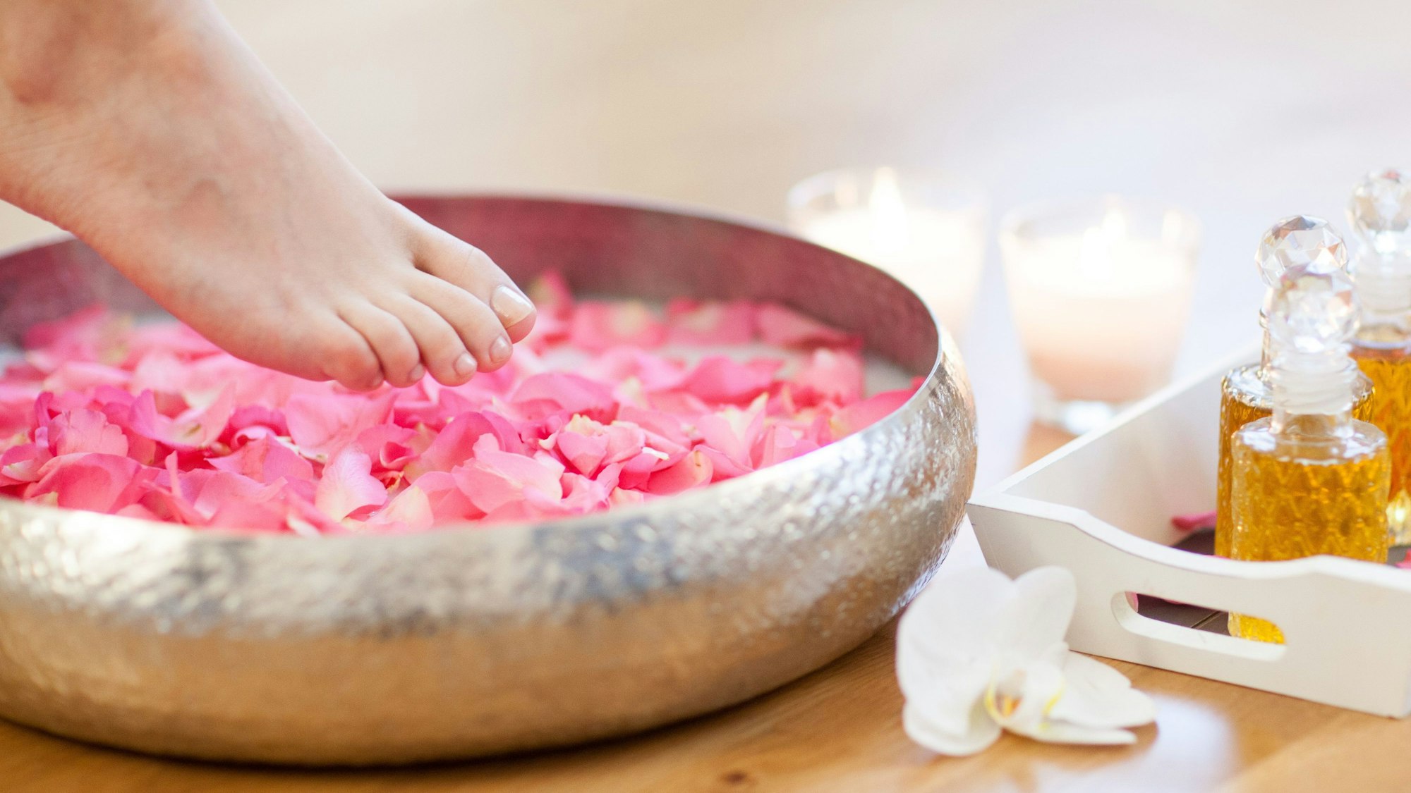 Ein Frauenfuß steigt in eine Schüssel mit Fußbad.