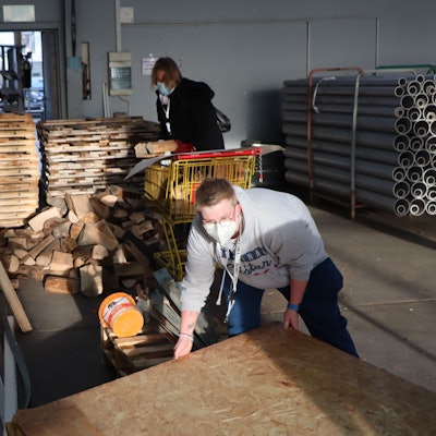 Männer stapeln Baustoffe in einer Halle.
