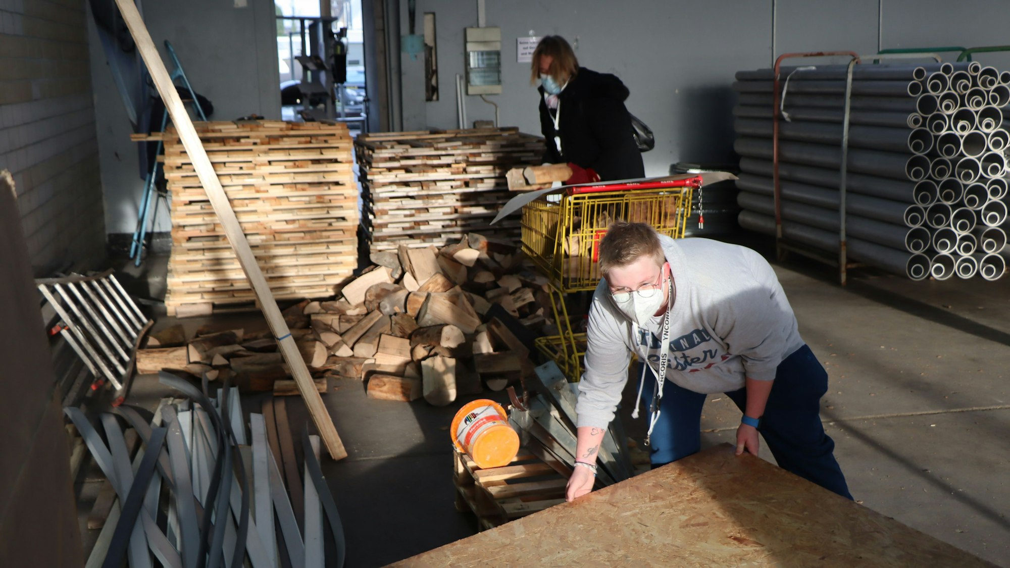 Männer stapeln Baustoffe in einer Halle.