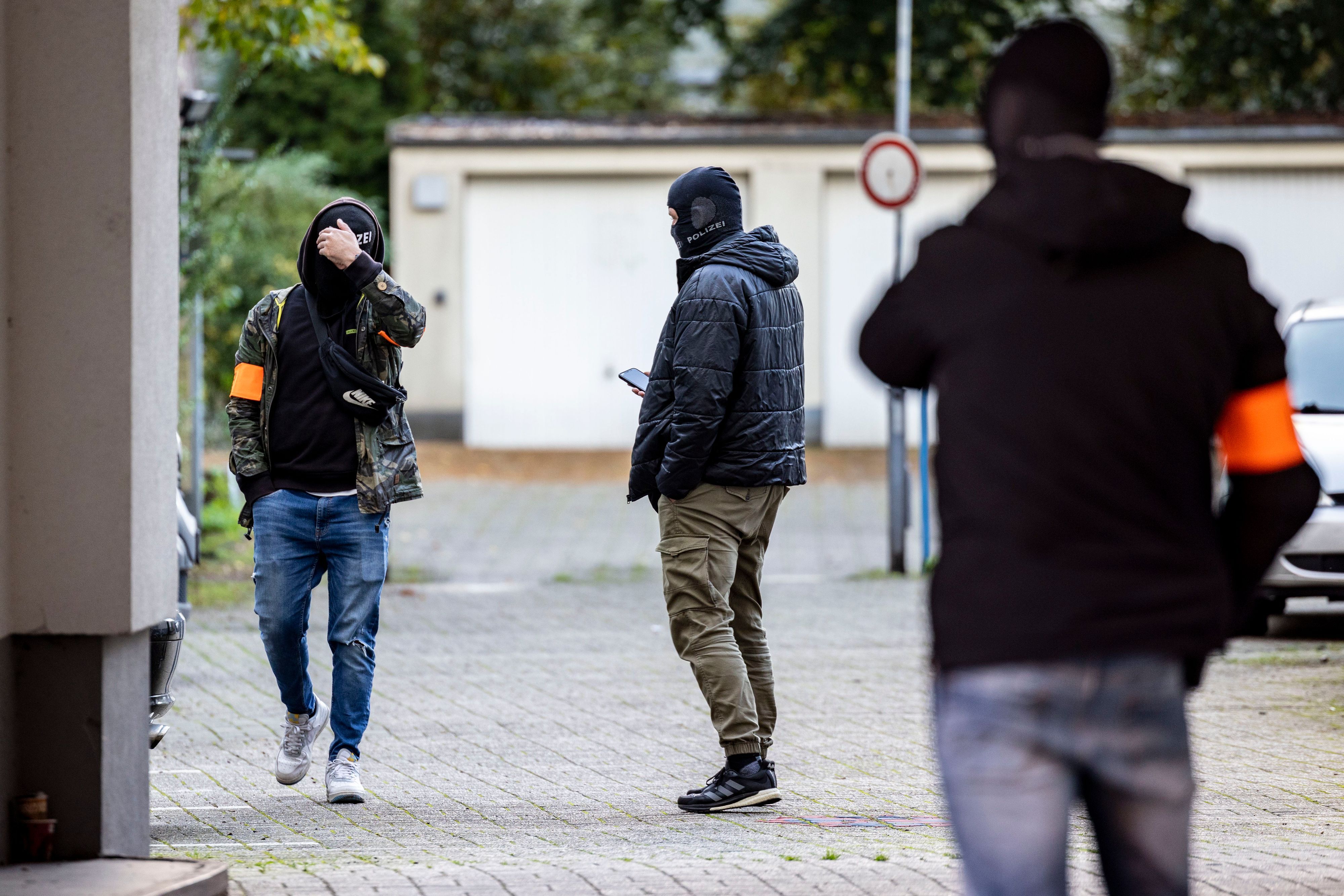 Drei Polizeibeamte stehen nach der Festnahme des Verdächtigen am Dienstagnachmittag auf dem Garagenhof des Hauses, in dem der Mann festgenommen wurde.