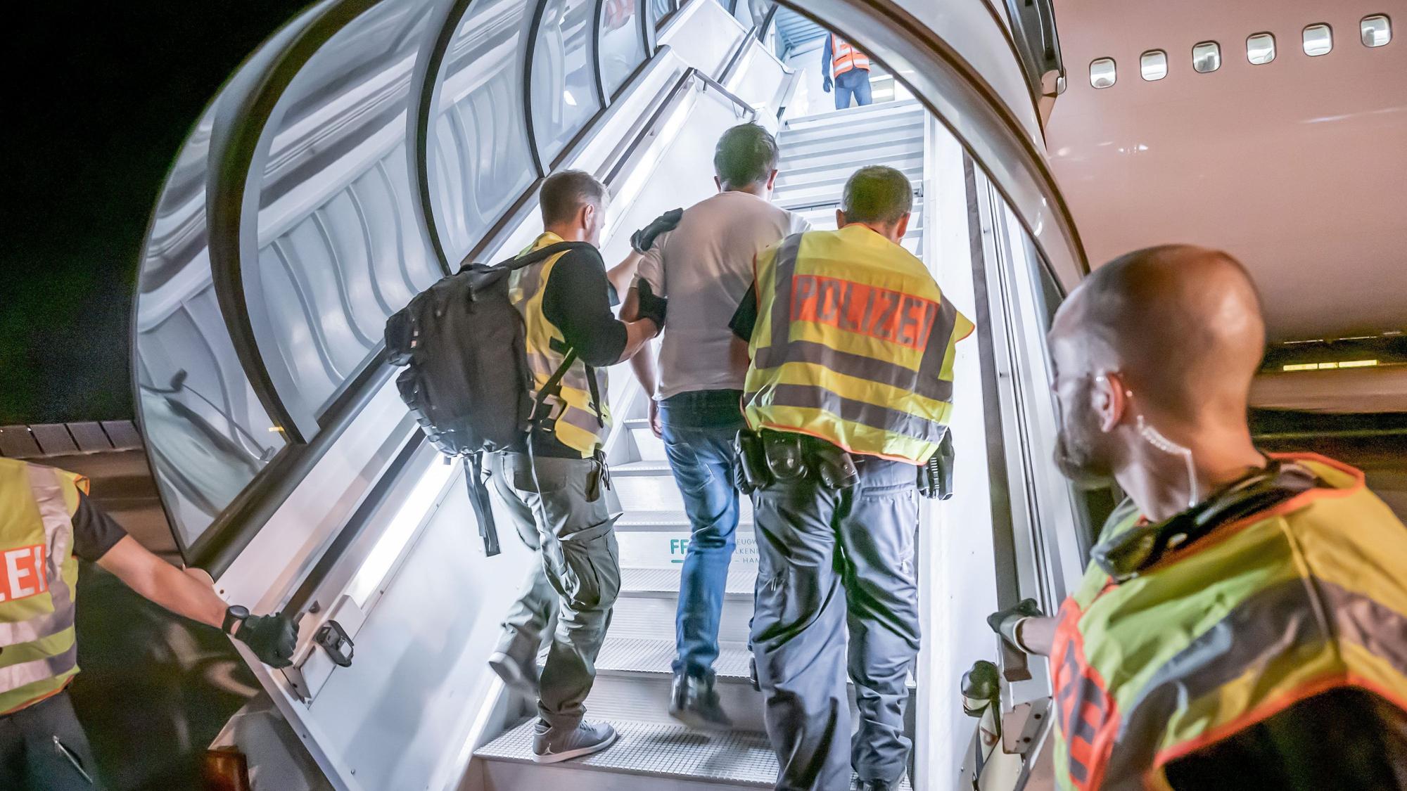 Polizeibeamte begleiten einen Afghanen auf dem Flughafen Leipzig-Halle in ein Charterflugzeug.