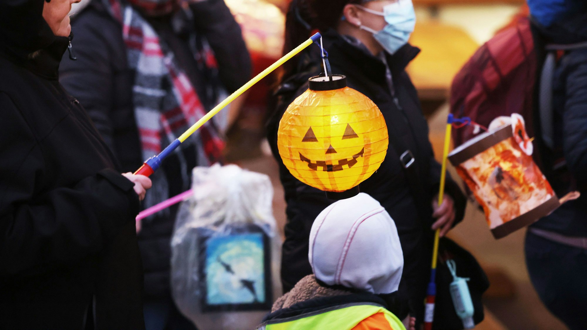 Eltern und Kinder gehen mit Laternen beim Martinsumzug durch die Straßen.