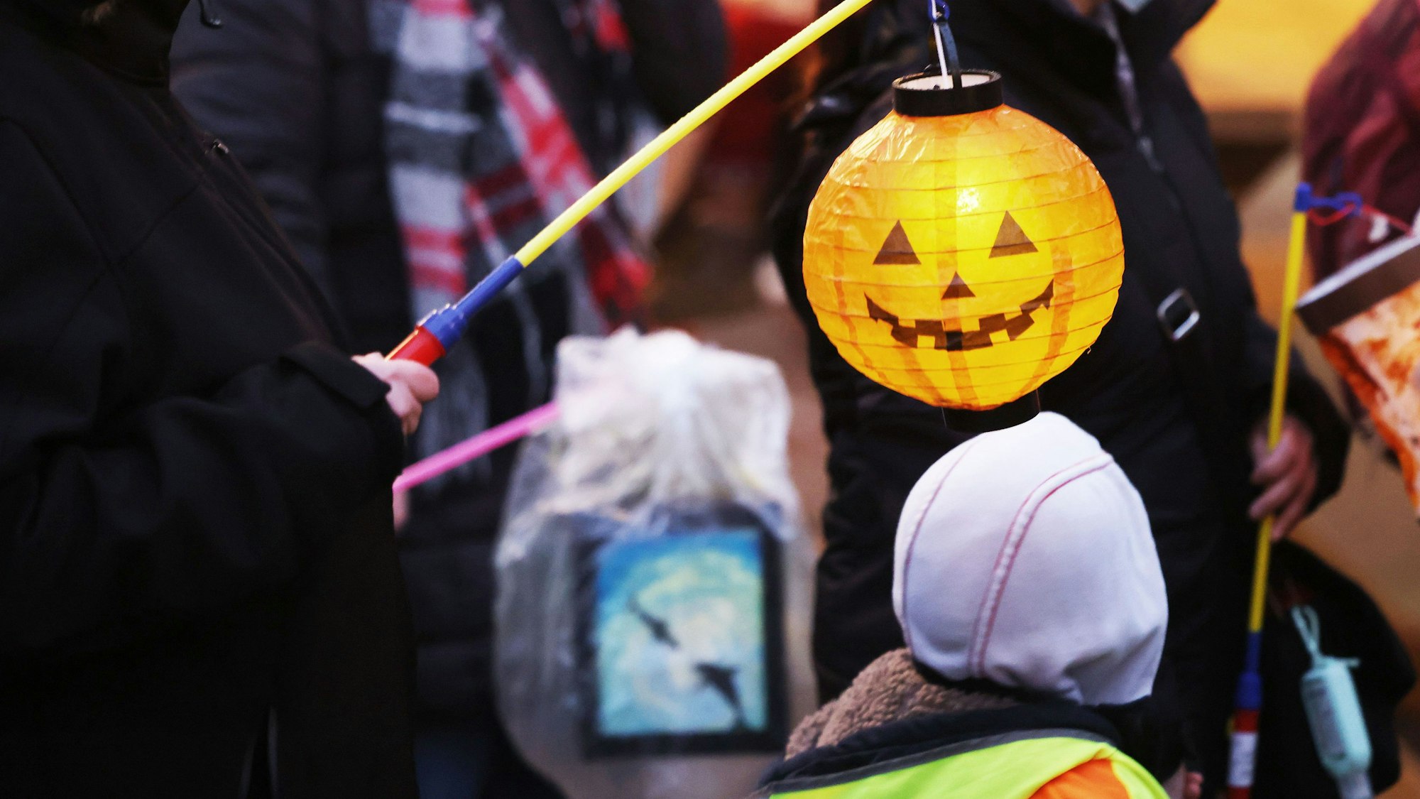 Eltern und Kinder gehen mit Laternen beim Martinsumzug durch die Innenstadt.