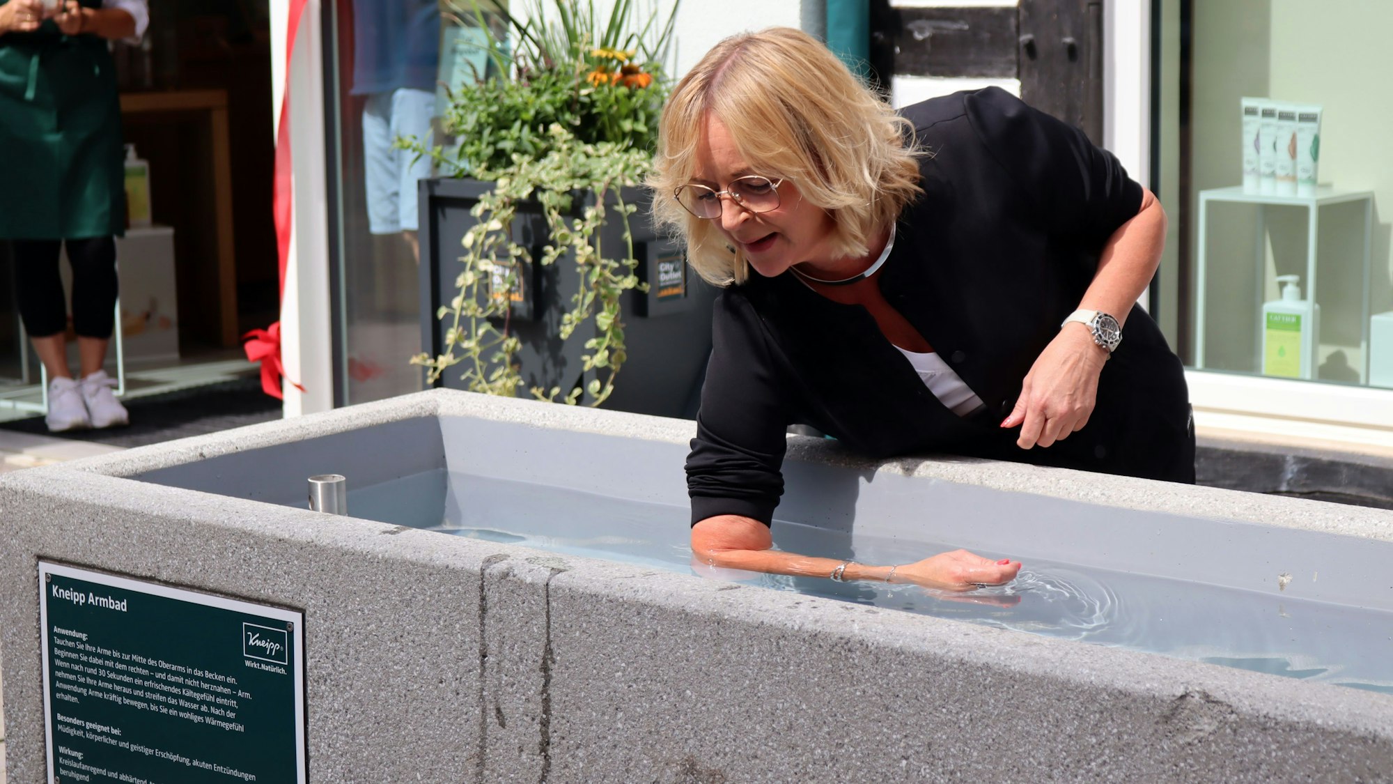 Bürgermeisterin Sabine Preiser-Marian nutzt das Kneipp-Armbad in der Orchheimer Straße, sie hat ihren rechten Unterarm im Wasser.