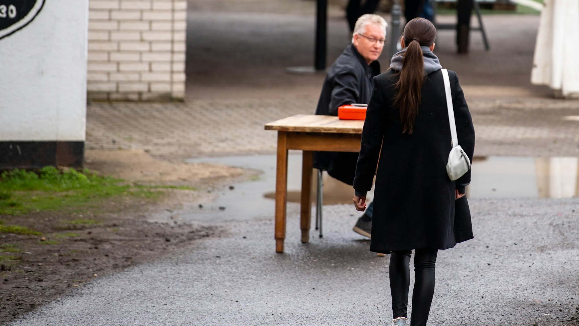 Das Bild zeigt eine junge Frau, die auf eine improvisierte Kasse zugeht.