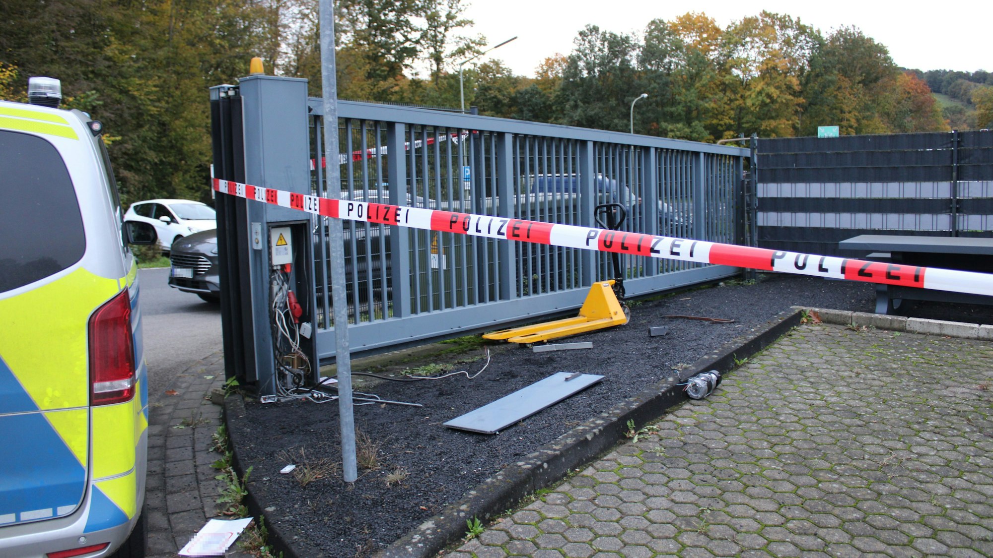 Polizei-Flatterban ist an einem Rolltor befestigt. Der Stromkasten am Rolltor wurde aufgebrochen. Links im Bild steht ein Polizeiwagen.