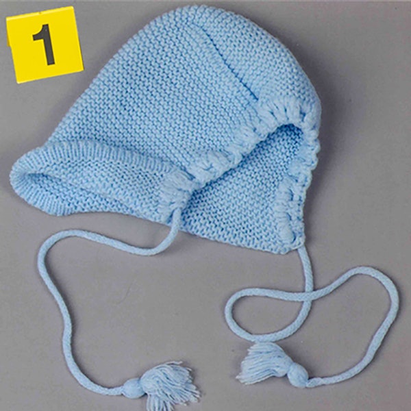 Eine hellblaue Babymütze liegt auf einem Tisch. Darüber steht ein gelbes Schild mit der Nummer 1.