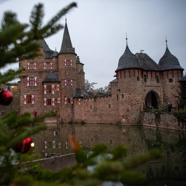 Neben einem geschmückten Weihnachtsbaum ist die Burg Satzvey zu erkennen.