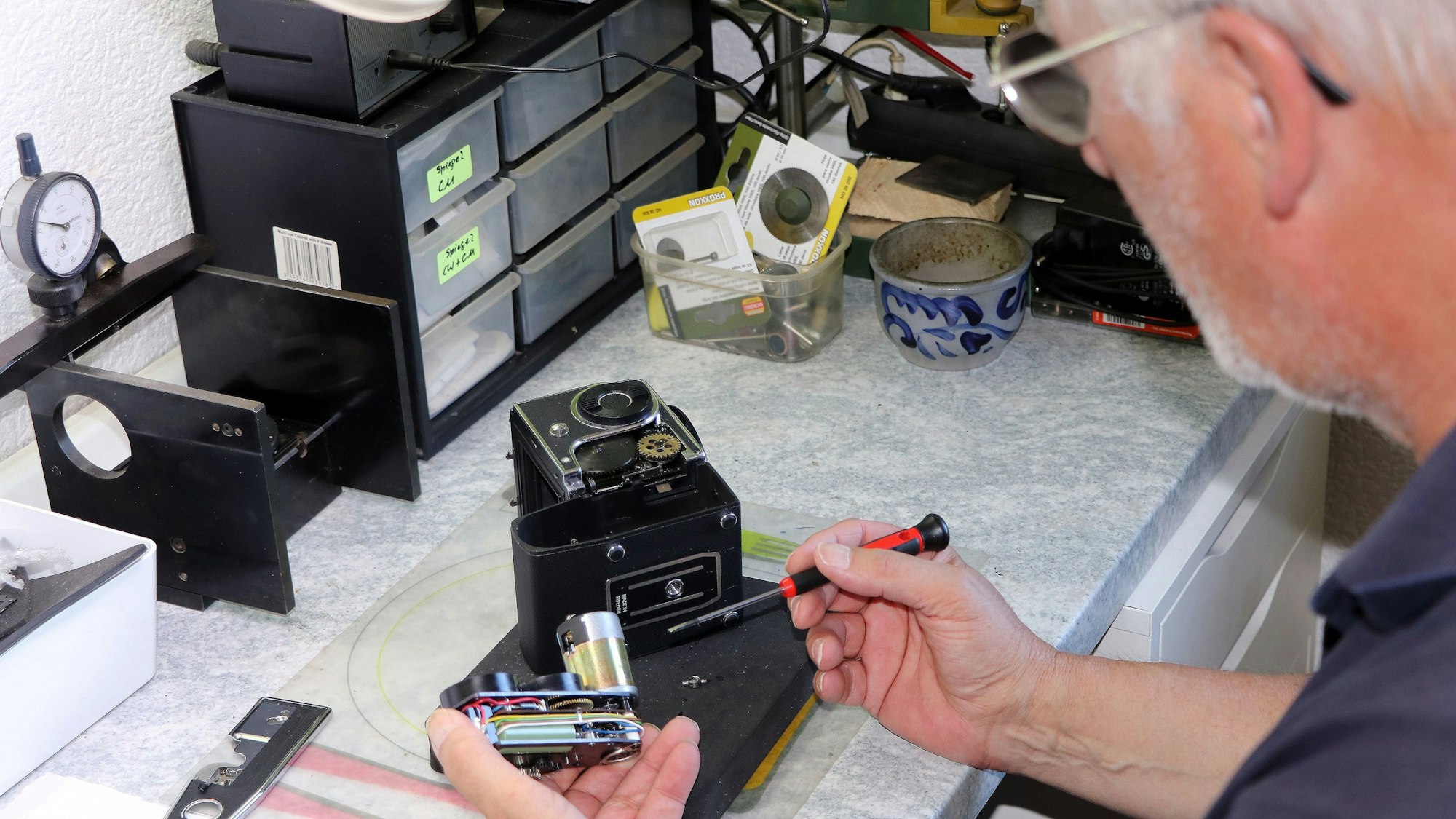 Auf dem Bild ist ein Mann zu sehen, der eine Kamera repariert.