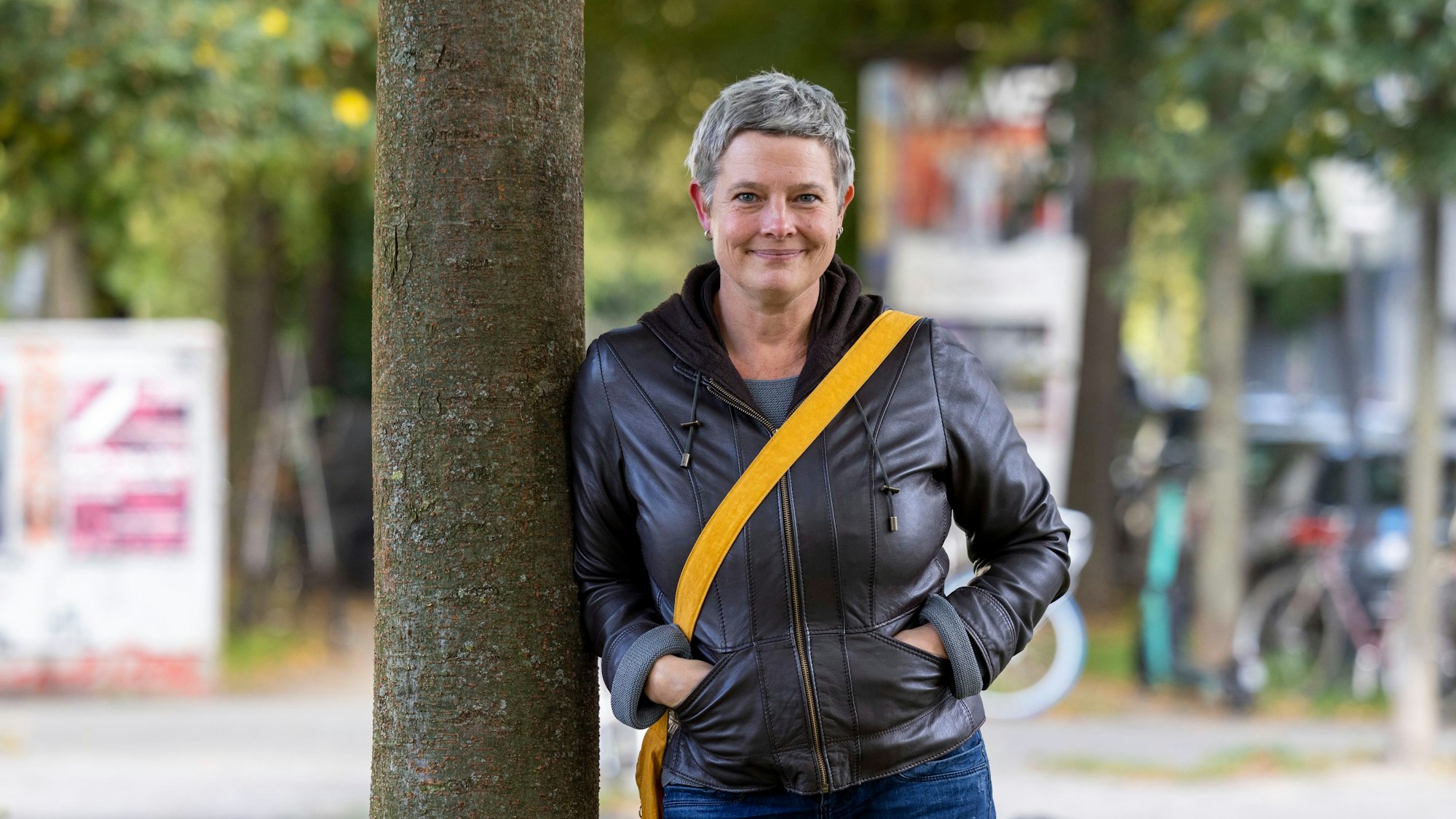 Anja Bierwirth steht an einen Baum gelehnt in einer Allee in der Kölner Südstadt.