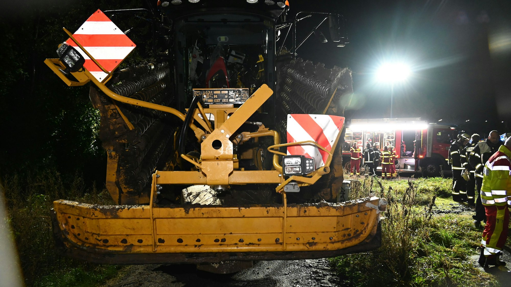 Ein Zug und eine Landmaschine stießen zusammen, der Schaden hielt sich aber in Grenzen. Einsatzkräfte stehen um die Landmaschine herum, im Hintergrund ist ein Feuerwehrwagen zu sehen.