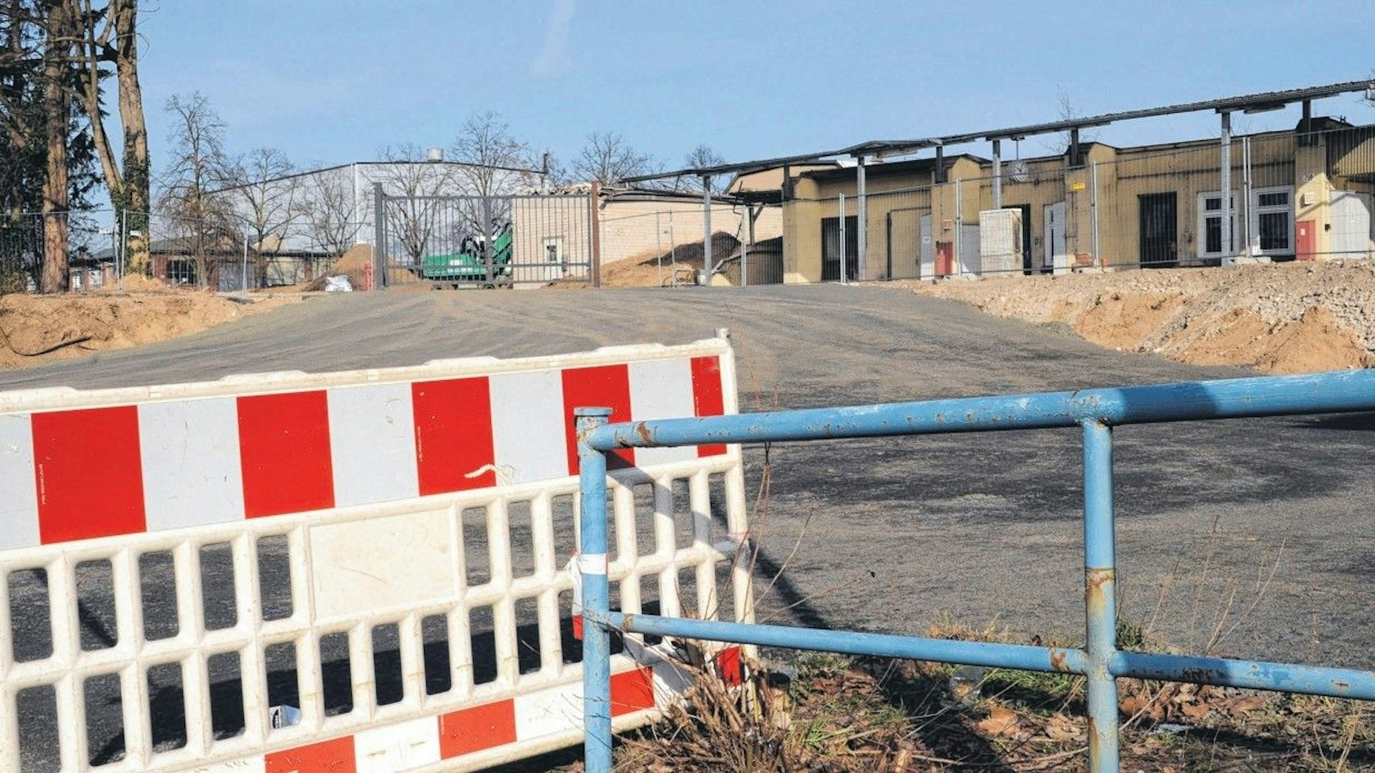 Eine rot-weiße Absperrung vor einem Industrie-Brachgrundstück.