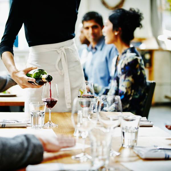 Kellnerin schüttet Wein in ein Glas in einem Restaurant Foto: Getty Images/Thomas Barwick