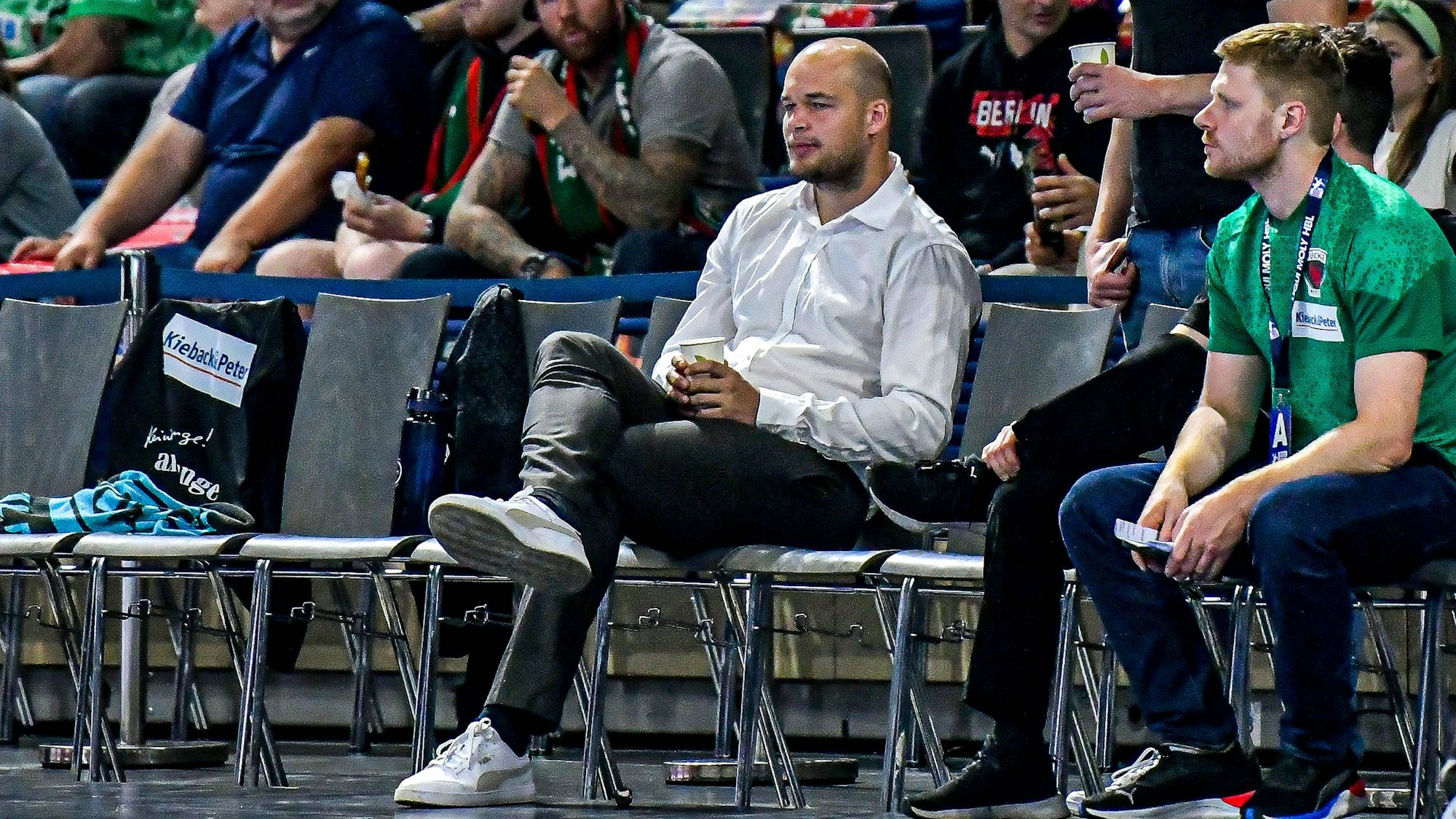 Handballer Paul Drux sitzt am Spielfeldrand eines Handballspieles und schaut zu.
