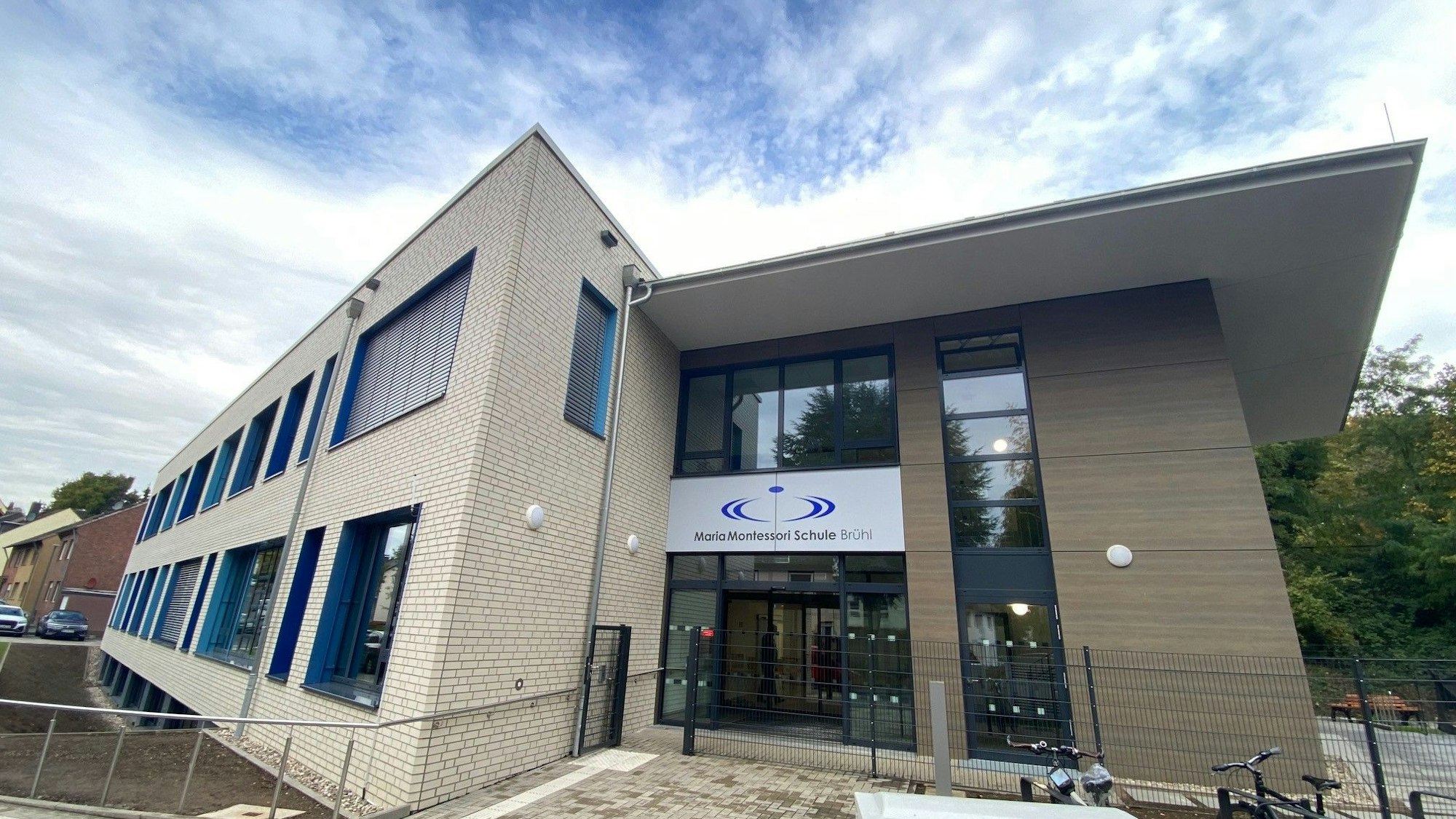 Zu sehen ist das Gebäude, dessen Fassade von weißem Klinker und großen Fenstern geprägt ist.