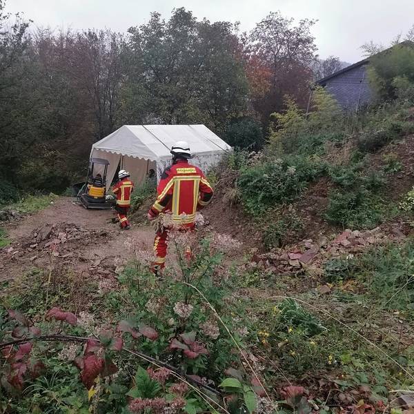 Feuerwehrleute am Hang mit dem Bagger.