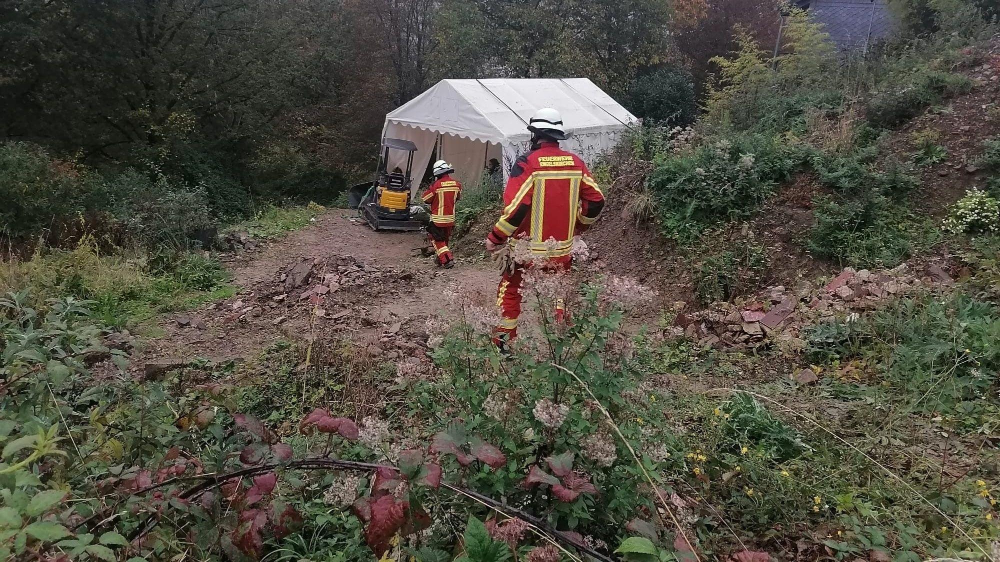 Feuerwehrleute am Hang mit dem Bagger.