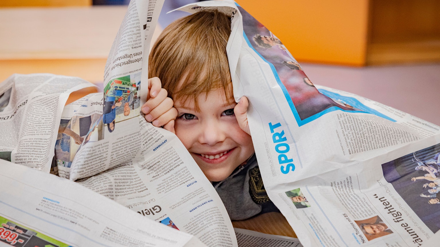 Ein kleiner Junge umgeben von Zeitungsseiten der Bonner Rundschau.