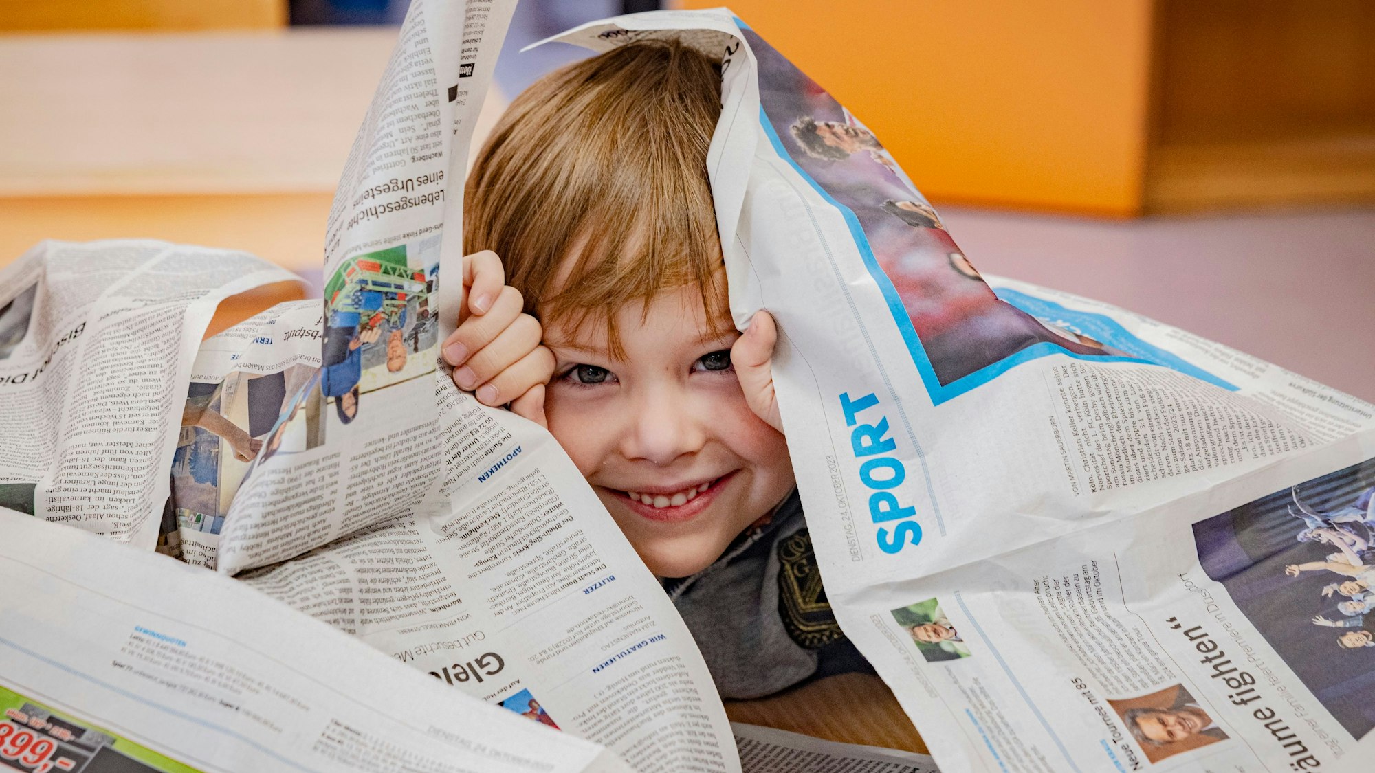 Ein kleiner Junge umgeben von Zeitungsseiten der Bonner Rundschau.