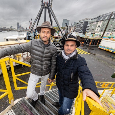 Die beiden stehen auf dem Zugang zu einem Fahrgschäft.