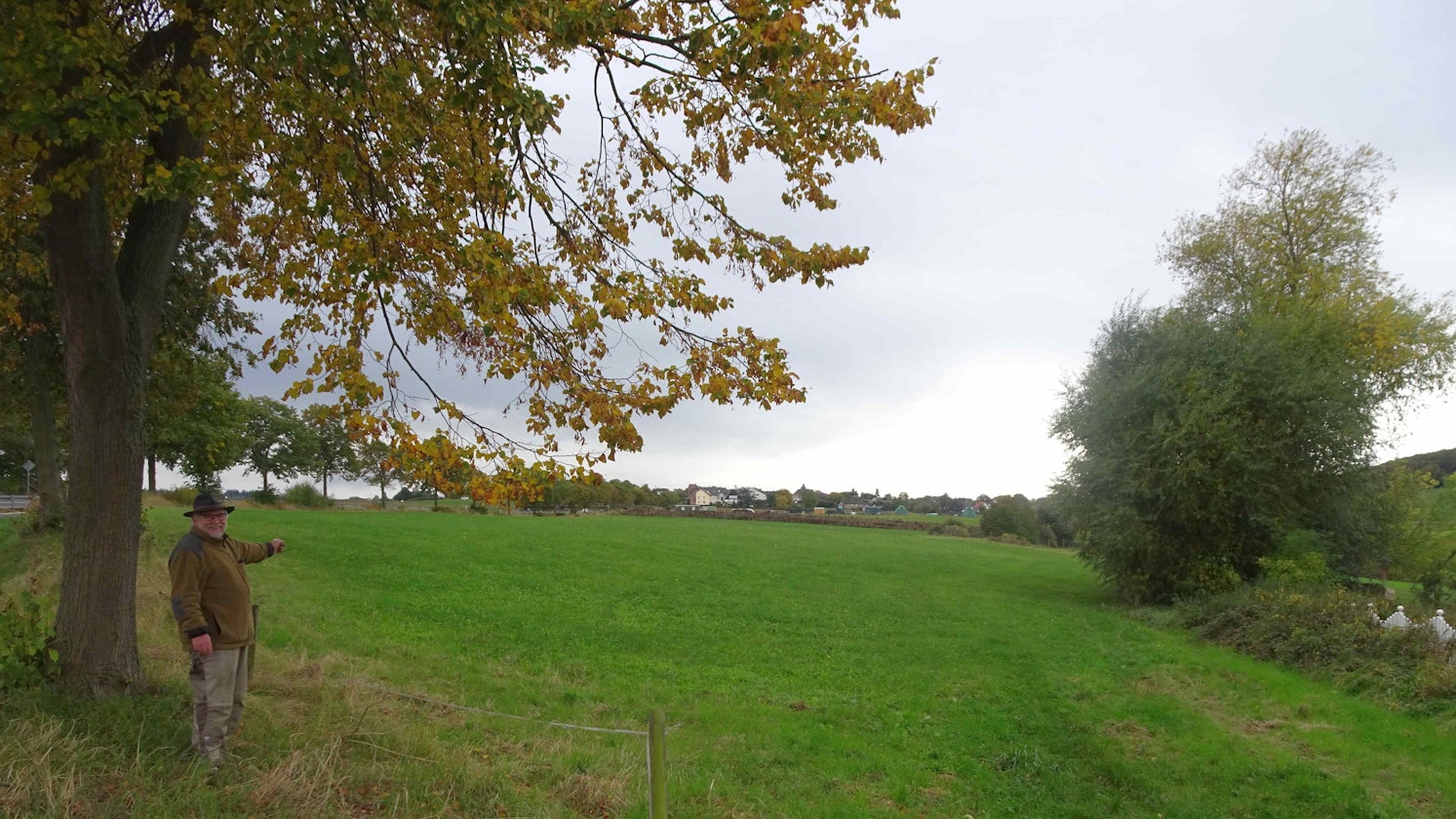 Rheinbachs Vize-Bürgermeister Karl Heinz Kerstholt (SPD) zeigt auf die Wiesenfläche an der Landstraße 113. Dort soll für die Höhenorte Merzbach und Neukirchen ein Discounter gebaut werden. Das Plangebiet ist knapp 5000 Quadratmeter groß.