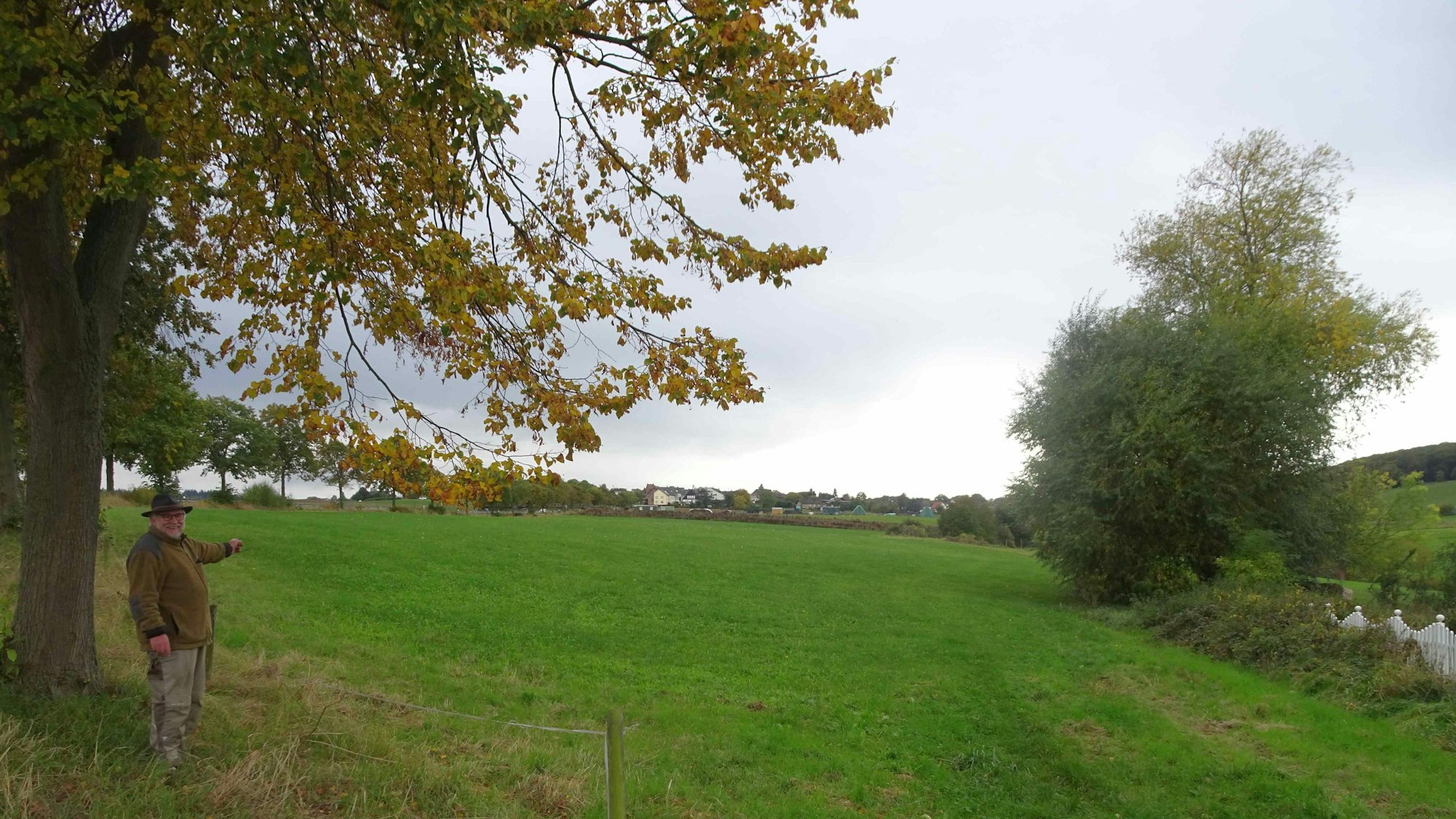 Rheinbachs Vize-Bürgermeister Karl Heinz Kerstholt (SPD) zeigt auf die Wiesenfläche an der Landstraße 113. Dort soll für die Höhenorte Merzbach und Neukirchen ein Discounter gebaut werden. Das Plangebiet ist knapp 5000 Quadratmeter groß.