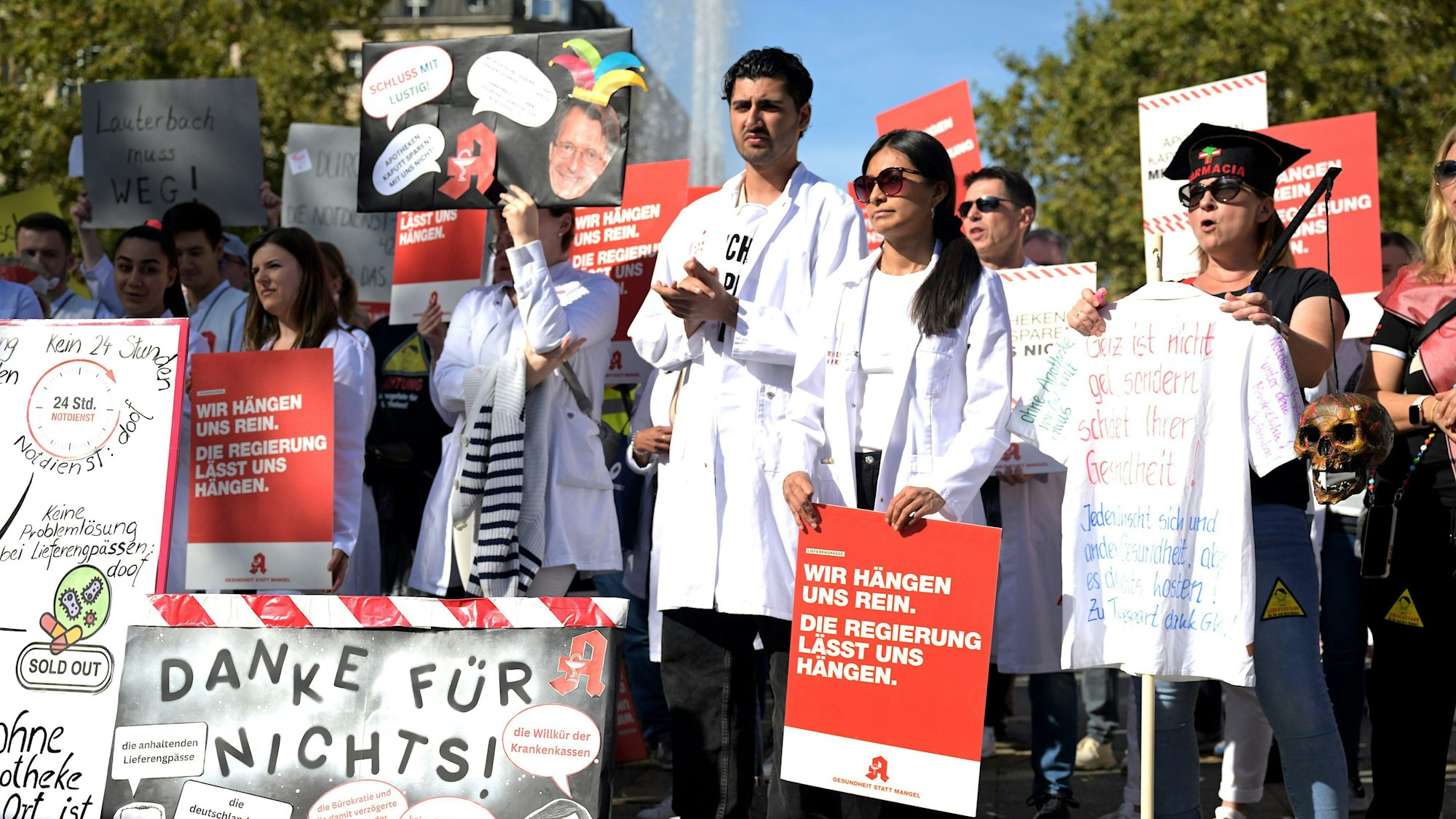 Demonstranten halten Schilder hoch und hören einem Redebeitrag zu.