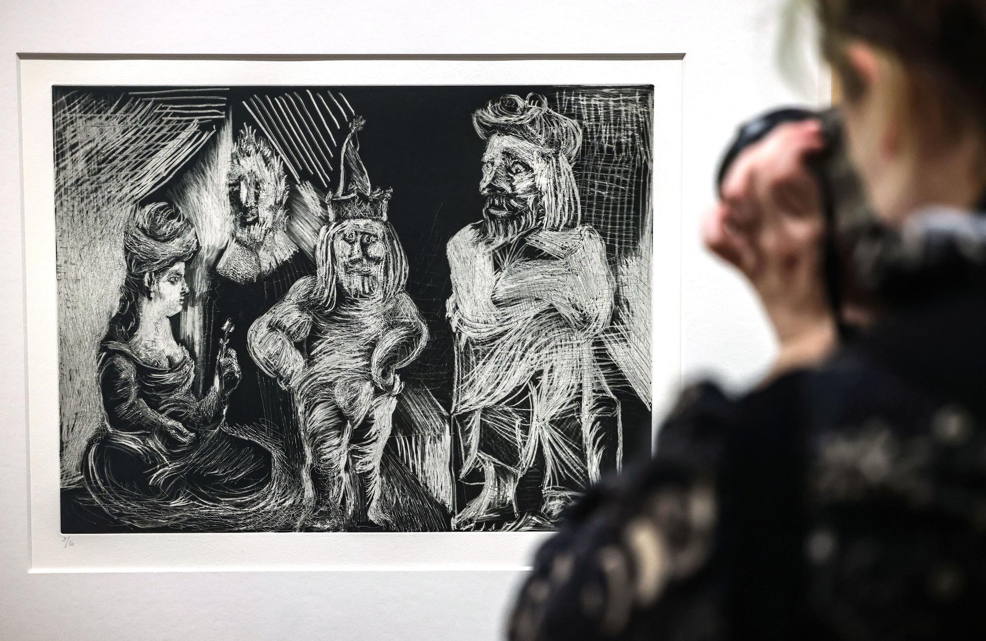 Eine Frau steht im Museum Ludwig vor der Radierung Frau mit Turban, alter Herr, Henker und Mann mit verrückten Augen von Pablo Picasso.