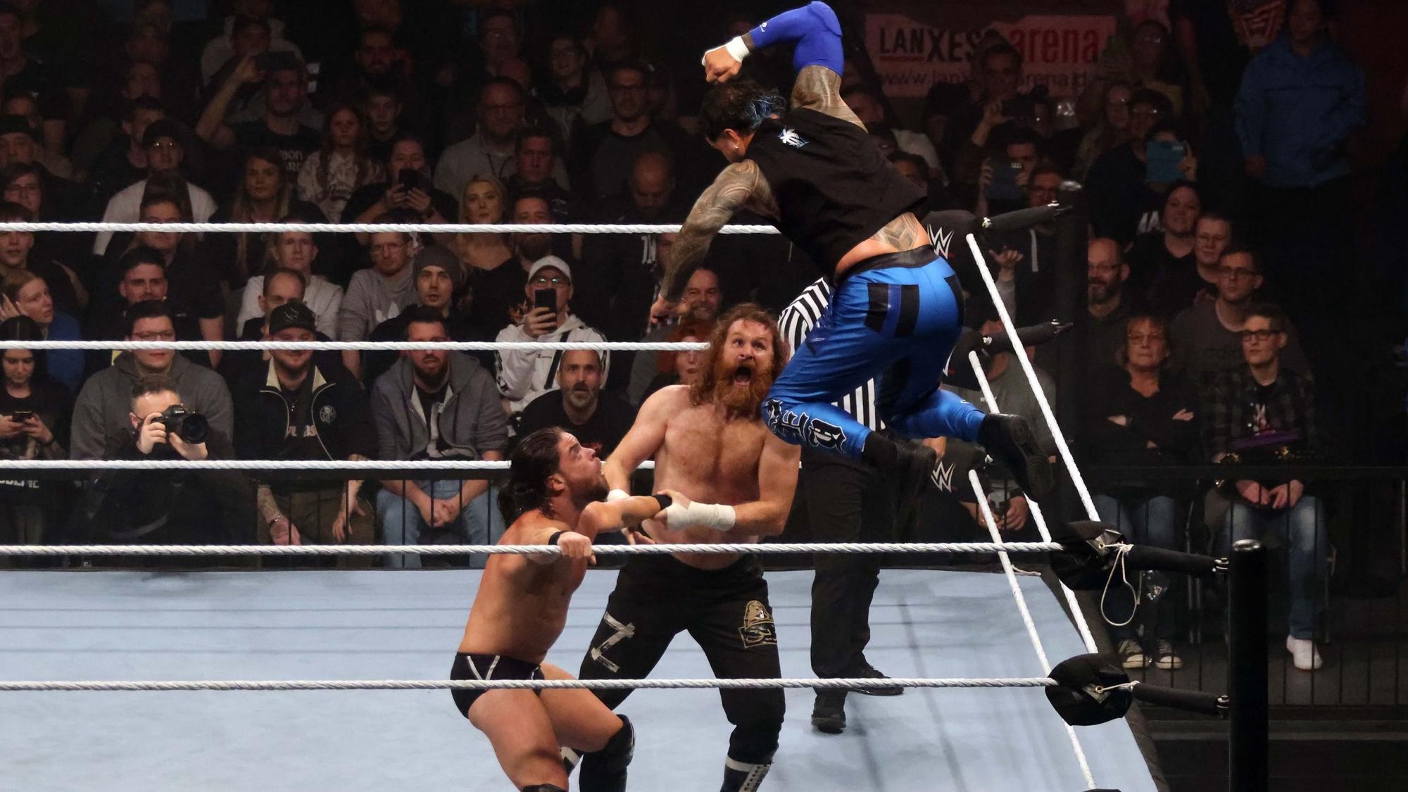 Drei Wrestler kämpfen im Ring der Arena.