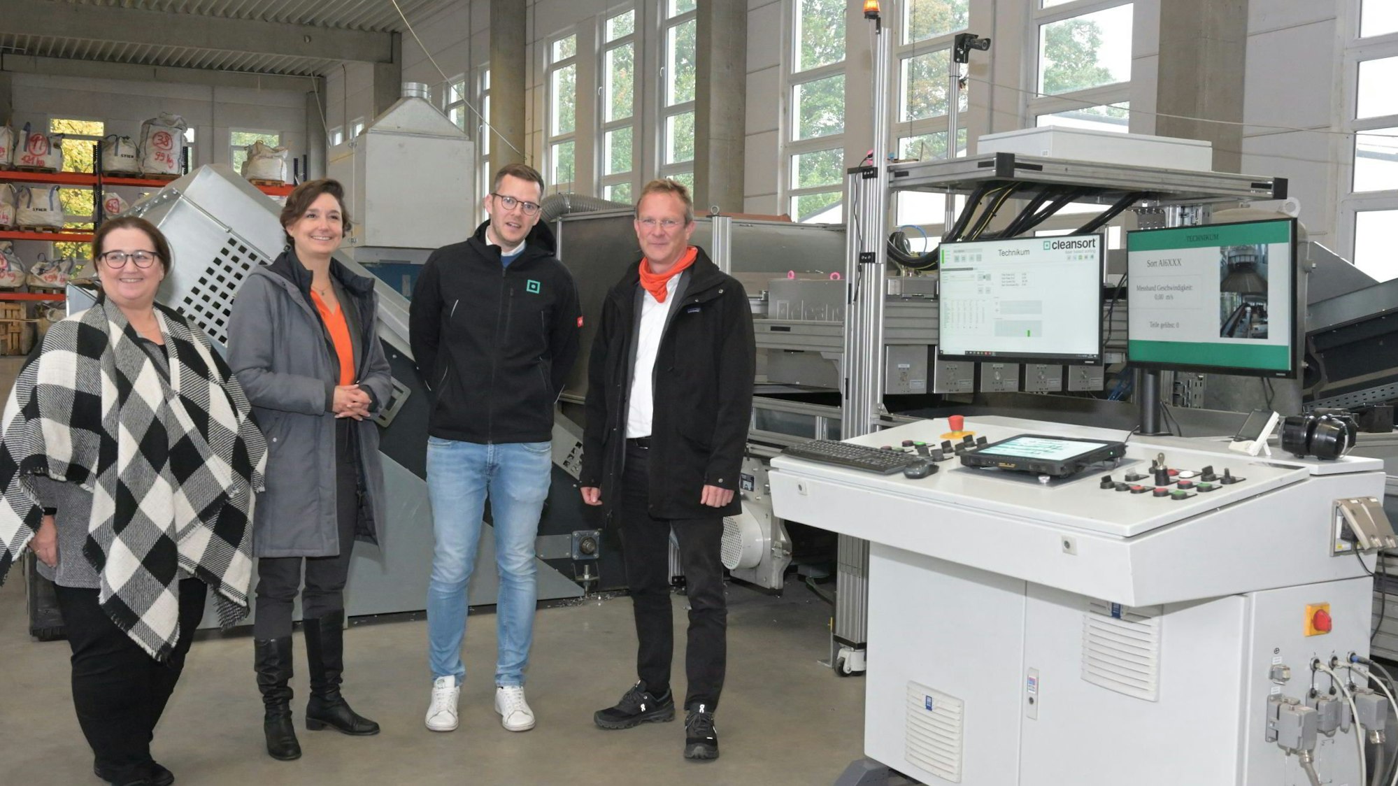 Eine Gruppe von Personen steht an einer technischen Anlage für das Recyceln von Aluminium-Schrott.