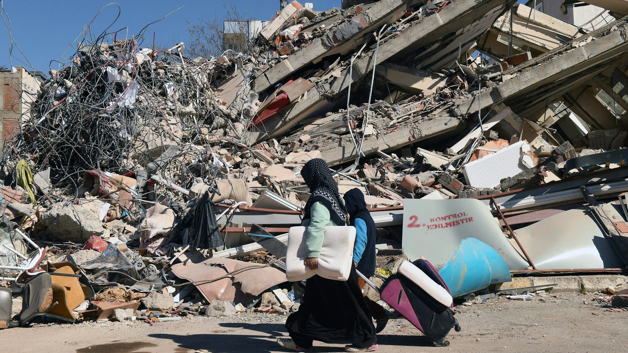 Türkei, Adiyaman: Menschen gehen an einem eingestürzten Gebäude vorbei
