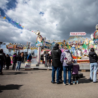 Menschen stehen vor einem bunten Fahrgeschäft.