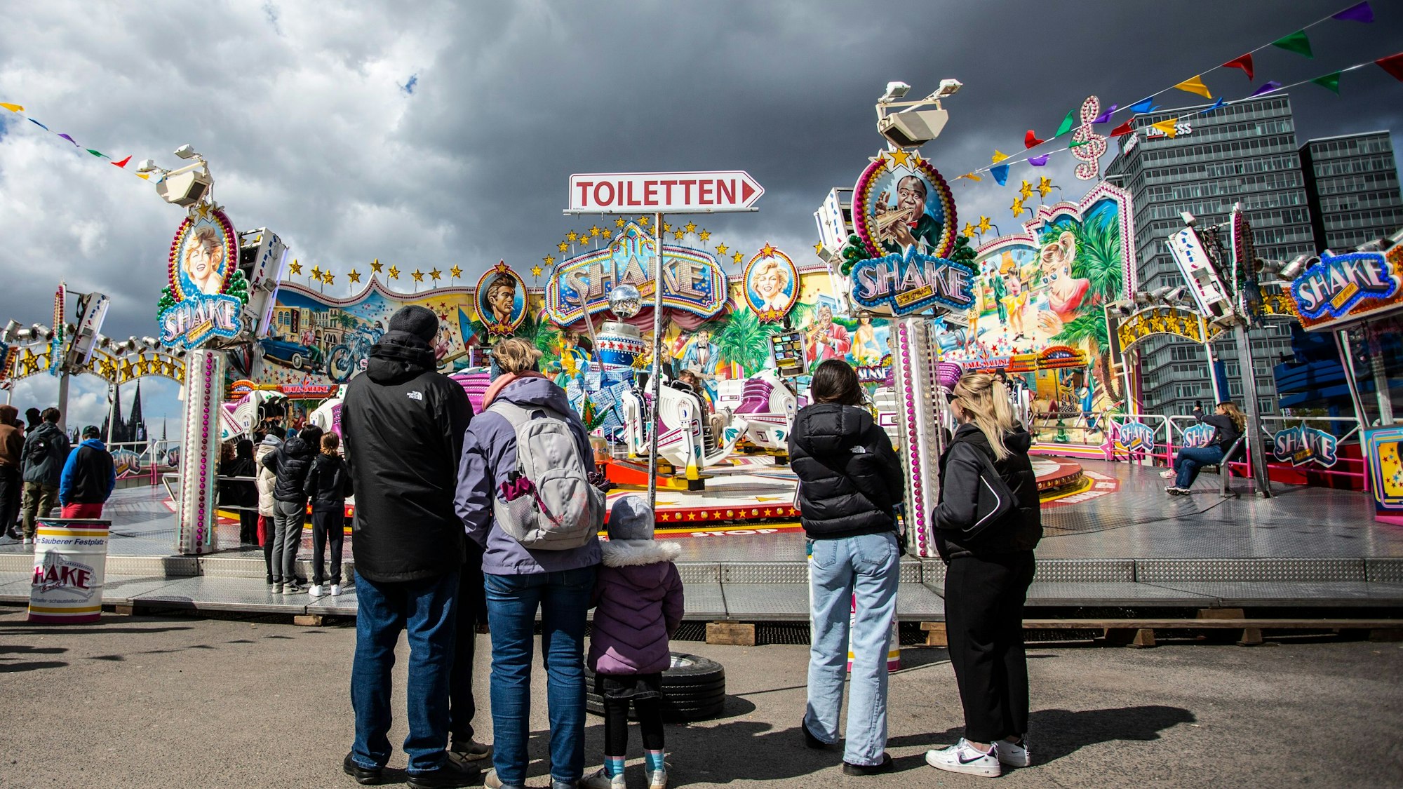 Menschen stehen vor einem bunten Fahrgeschäft.